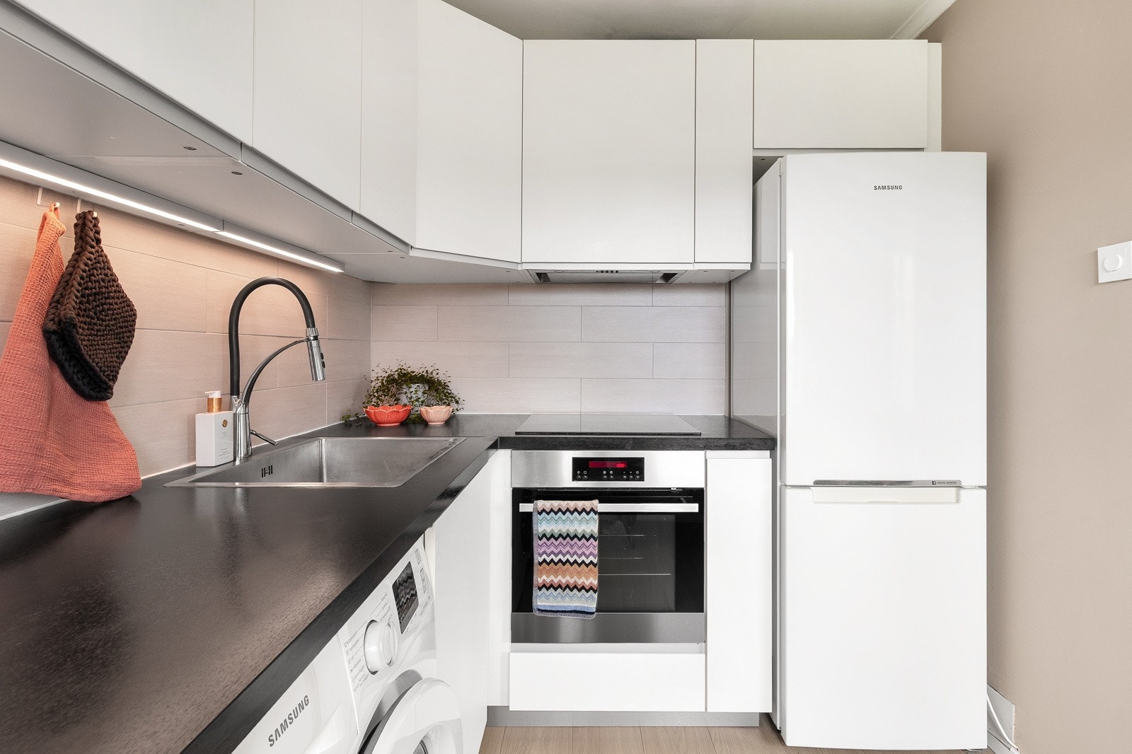 Kjøkkeninnredningen har hvite høyglansfronter og byr på hvitevarer som kjøleskap, fryseskap, platetopp, ventilator, steovn og vaskemaskin medfølger. Galleribilde