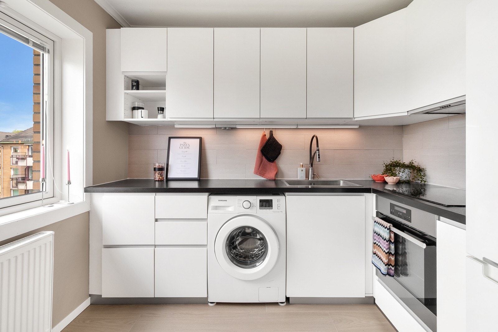 Kjøkkenet i leiligheten er romslig og moderne og har rikelig med oppbevaringsplass i skuffer og skaper. Galleribilde