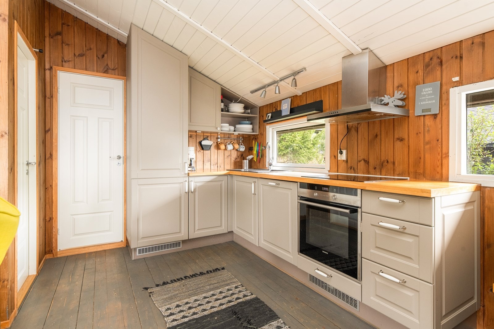 På kjøkkenet er det innredning i en dus grå fargetone, med plass til alt du måtte trenge på hytta. Benkeplate i heltre med godt arbeidslys fra vindu over benken. Galleribilde