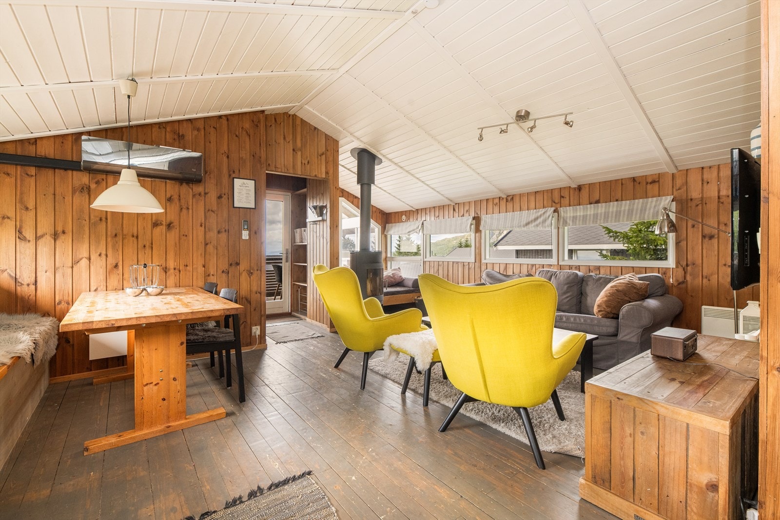 Med adkomst fra overbygd inngangsparti/terrasse er det gangareal med plass til sko- og ytterklær. Her er det tregulv og beiset panel på veggoverflatene i en varm, brun fargetone som går videre inn i hytta og gir en lun atmosfære. Galleribilde