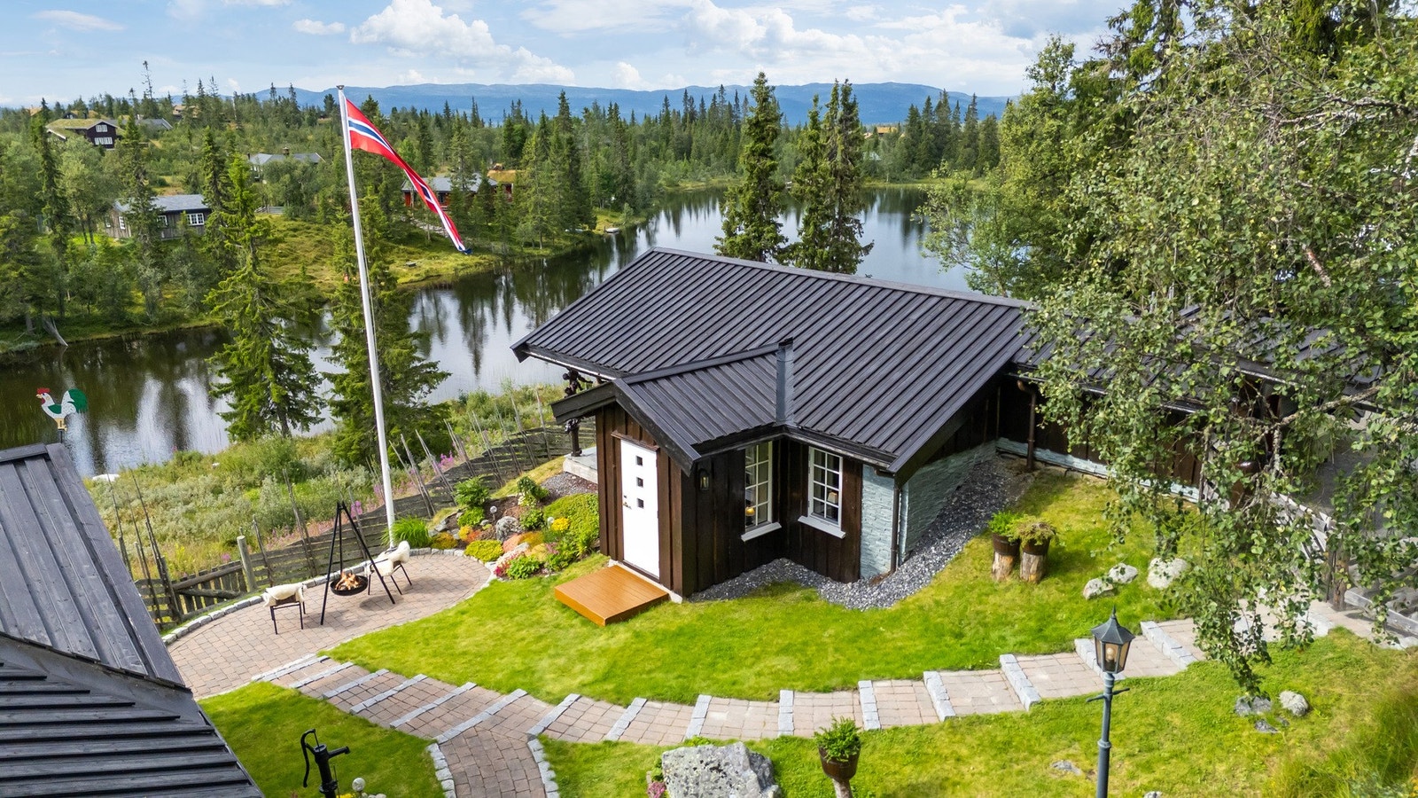 Meget pent opparbeidet tomt med bed, stauder, belegningstein i trapper og arealer rundt bebyggelsen Galleribilde