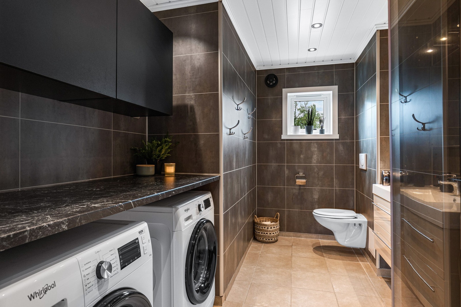 Baderommet har godt med oppbevaring i vegghengte skap og varme i gulv Galleribilde