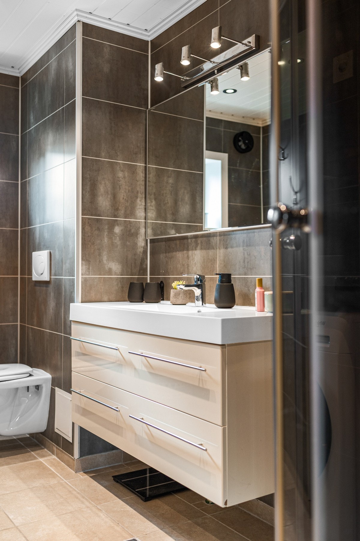 Delikat baderom bestående av servant med underskuffer, vegghengt toalett og dusjkabinett Galleribilde