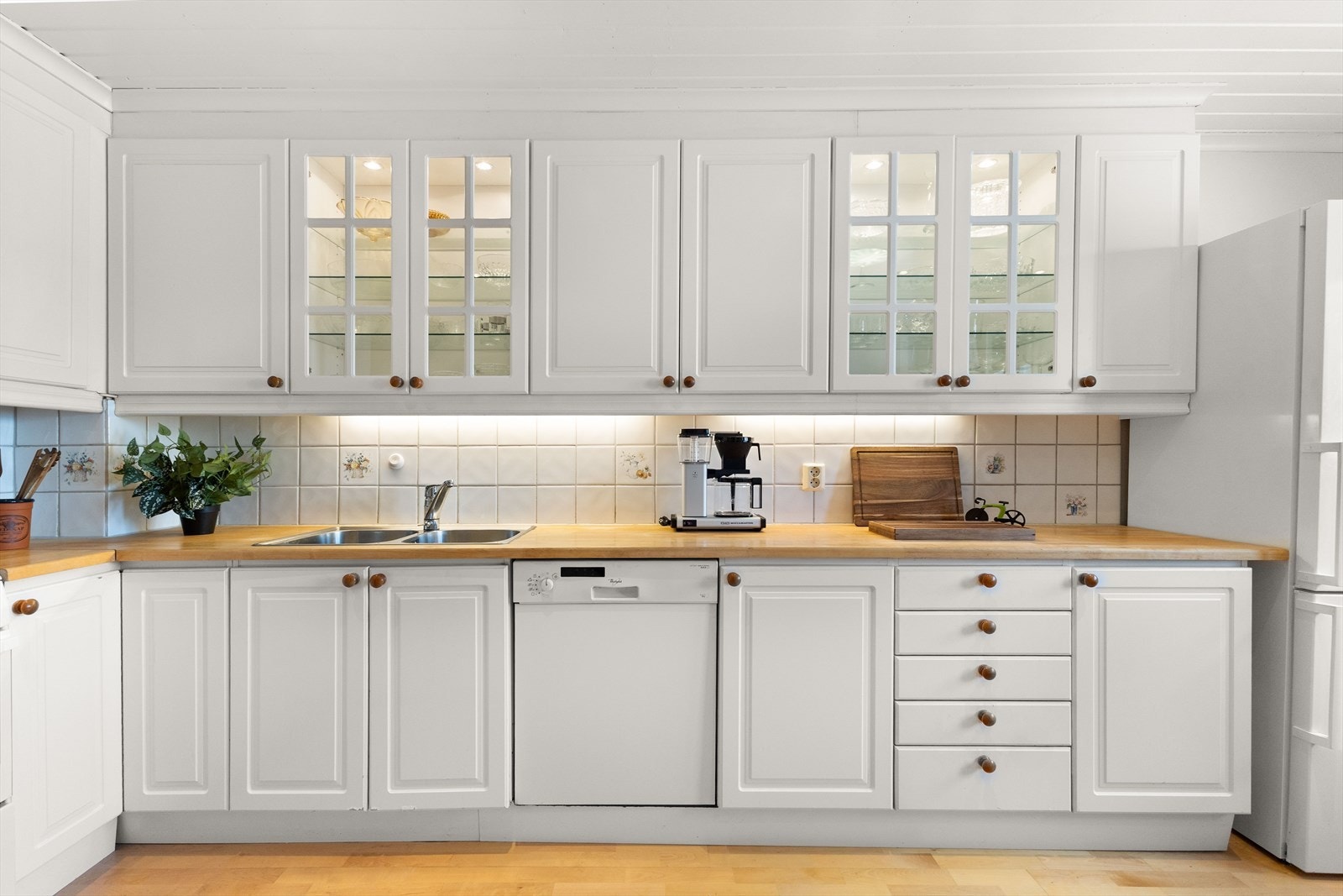 Flislagt vegg over benkeskap og belysning under overskap. Galleribilde