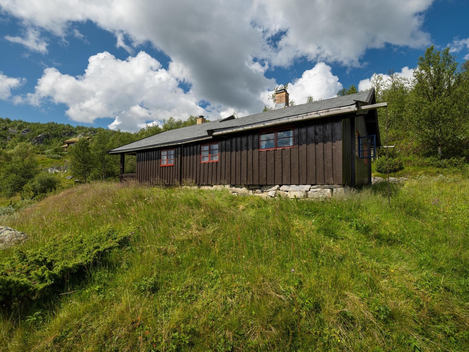 På hyttens tilbygde del er yttervegger oppført i bindingsverk som er kledd utvendig med trepanel Galleribilde