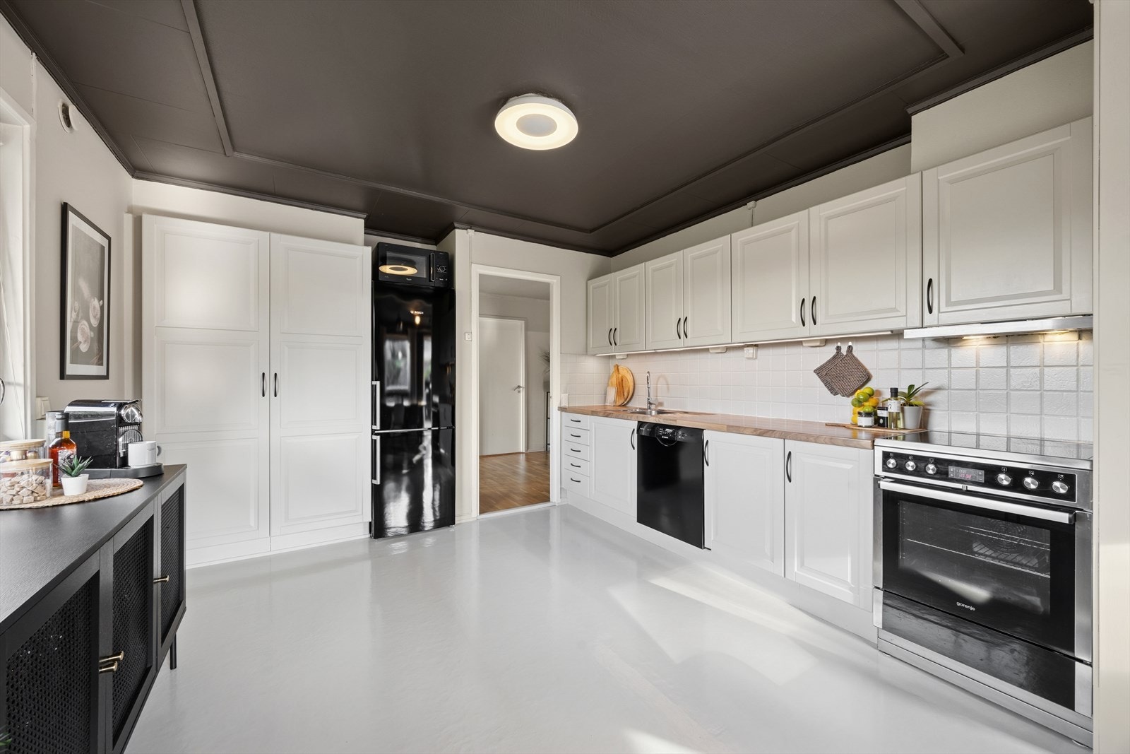 Boligens kjøkken er romslig. Kjøkkeninnredning fra 2012 av merket Ikea. Innredningen har lyse profilerte fronter. Det er laminerte benkeplater med nedfelt oppvaskkum i rustfritt stål, ett-greps vannkran. Galleribilde