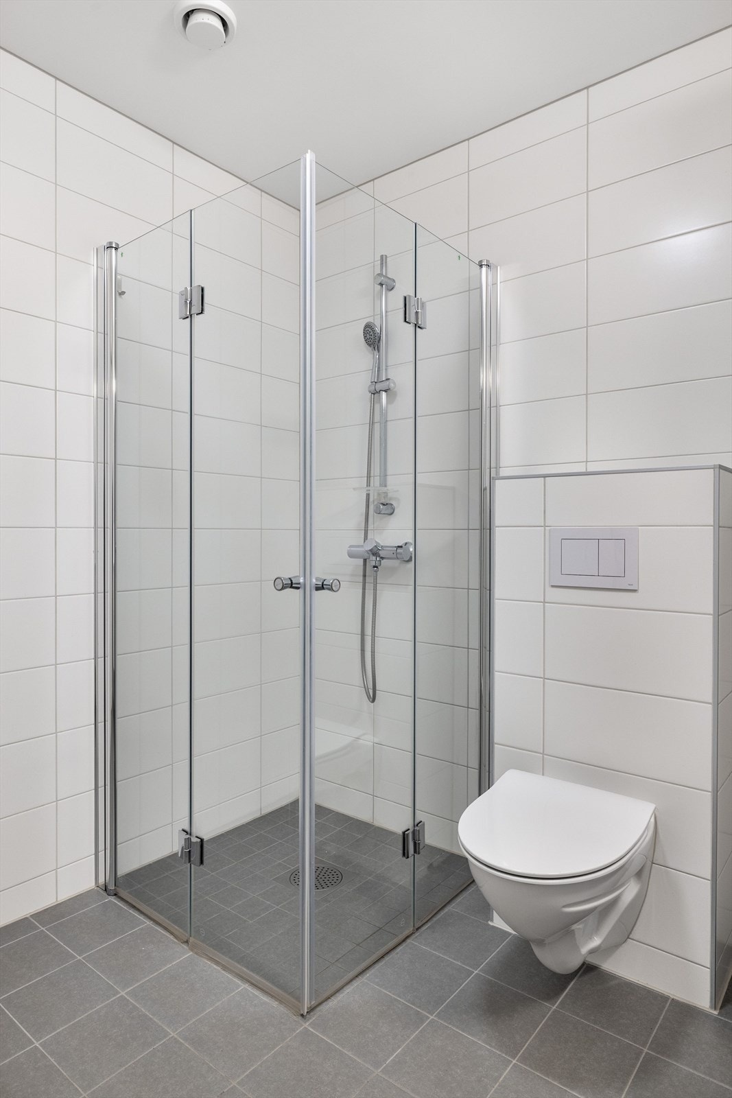 Badet også utstyrt med dusjhjørne med innfellbare glassdører med vegghengt dusjbatteri, samt vegghengt toalett. Galleribilde