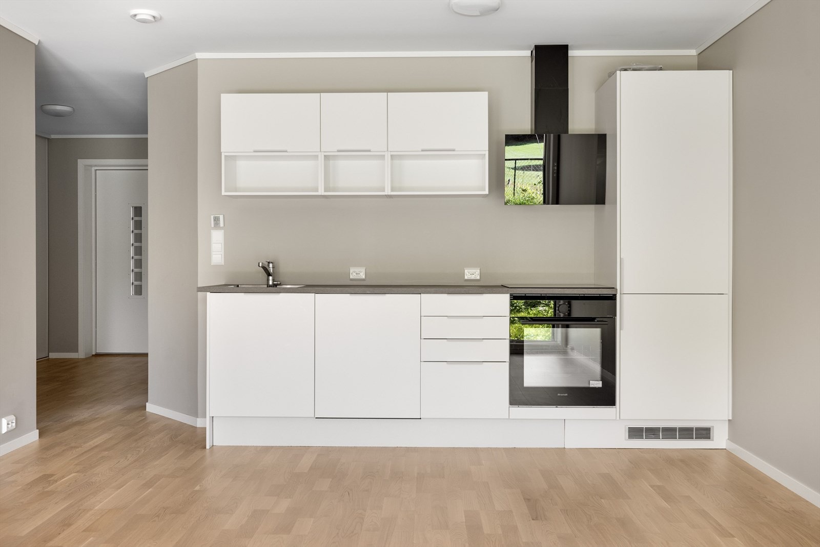 Pent kjøkken fra 2022 med hvite, glatte fronter og laminert benkeplate ned nedfelt oppvaskkum. Galleribilde