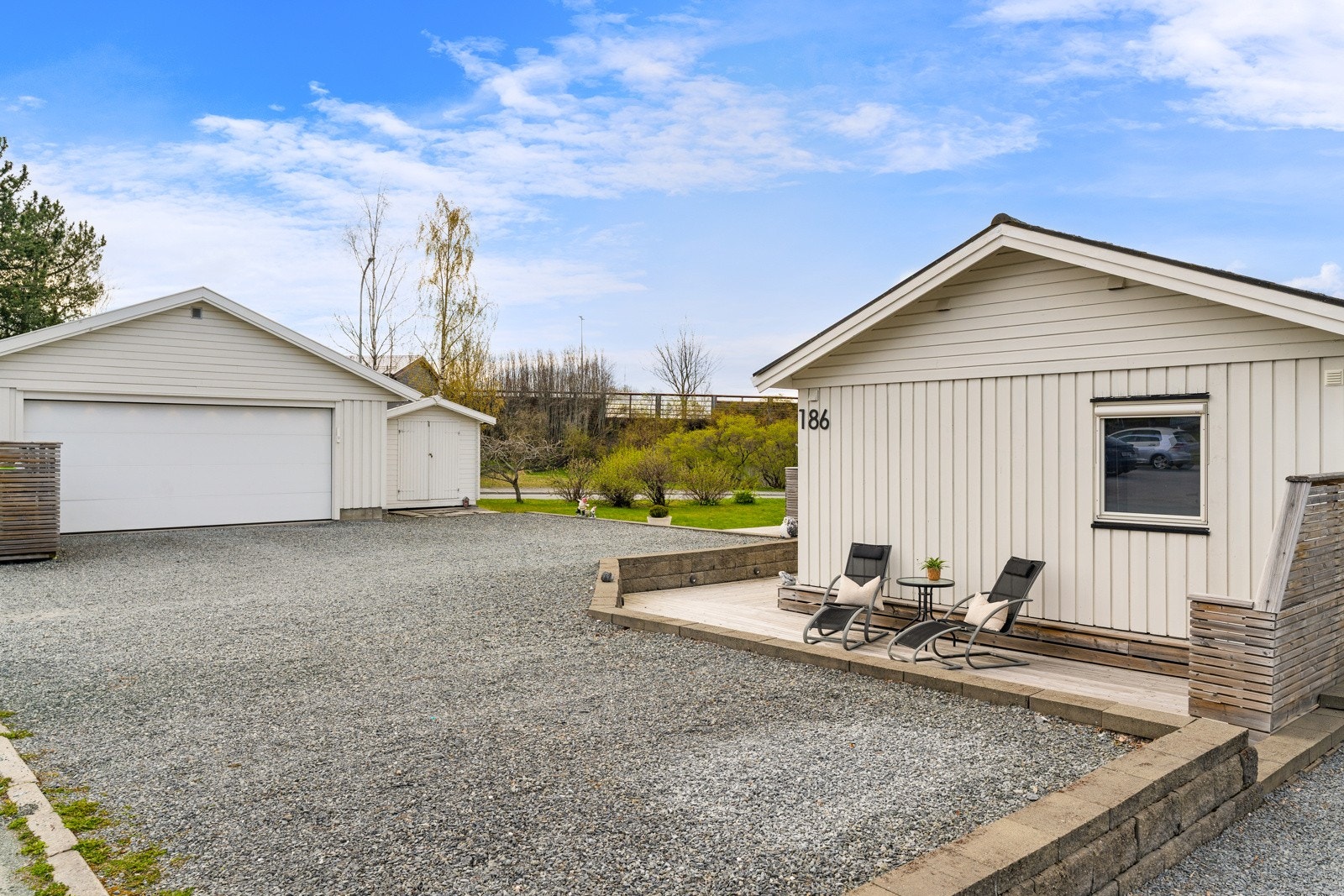 Boligen står på en romslig tomt med gruslagt gårdsplass, en frittstående dobbelgarasje med elbillader og stor hage. Ved garasjen er det også en egen bod med god plass til utemøbler, verktøy og annet utstyr. Galleribilde