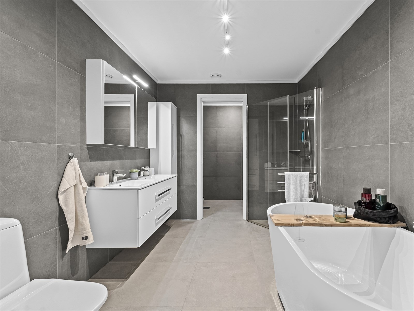 Moderne fliselagt bad med stilrent design. Vaskerom med skyvedør i enden. Galleribilde