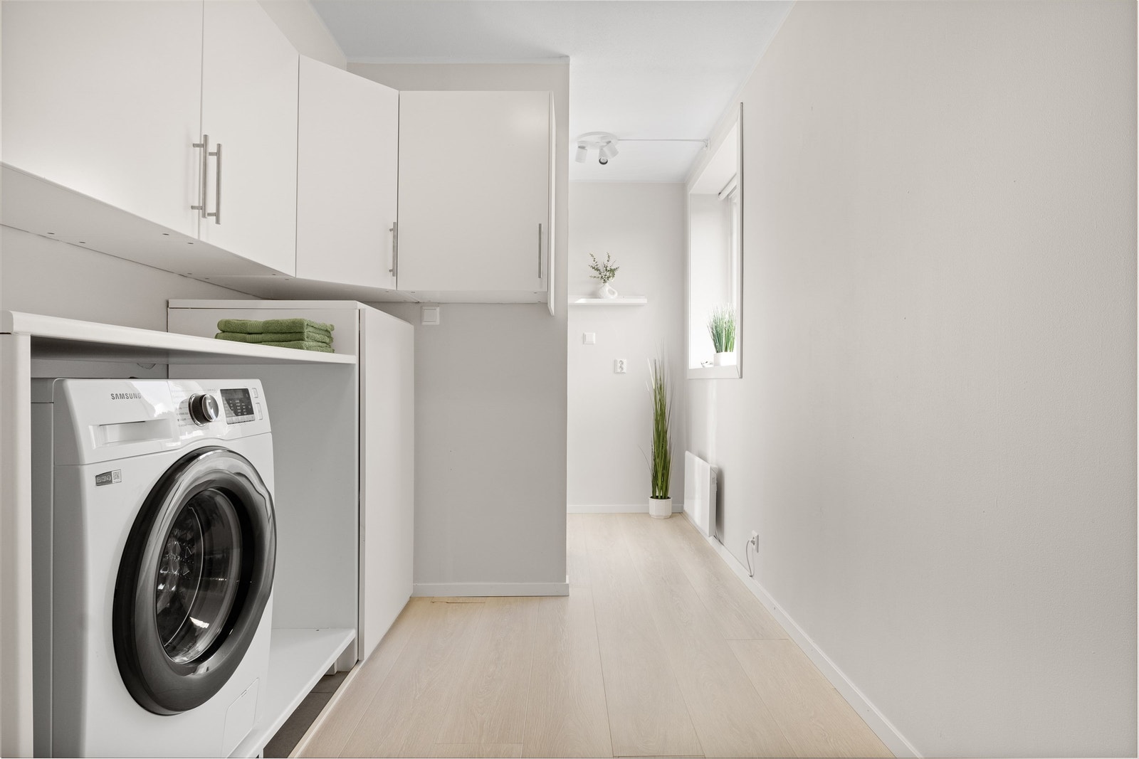 Praktisk løsning i gang/vaskerom med opplegg for vaskemaskin og rikelig med oppbevaringsmuligheter. Galleribilde