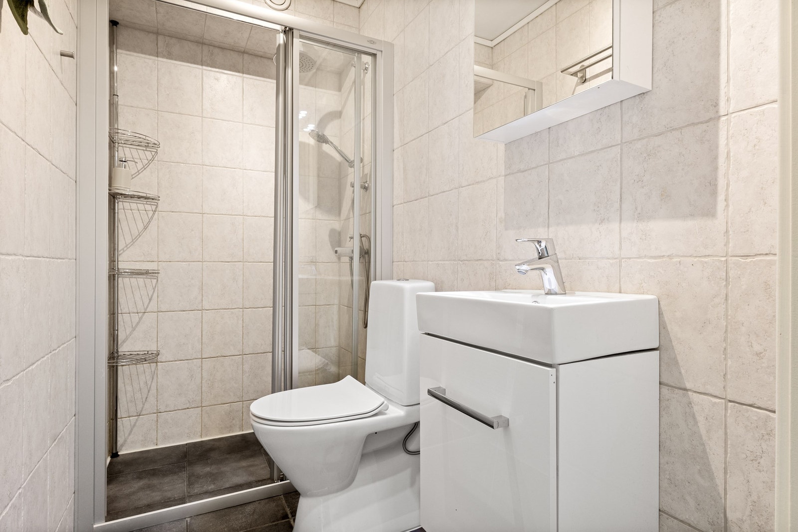 Boligens andre bad er helfliset og innredet med vegghengt servantinnredning, speil med overlys, gulvstående toalett og dusjnisje med dusjarmatur. Galleribilde