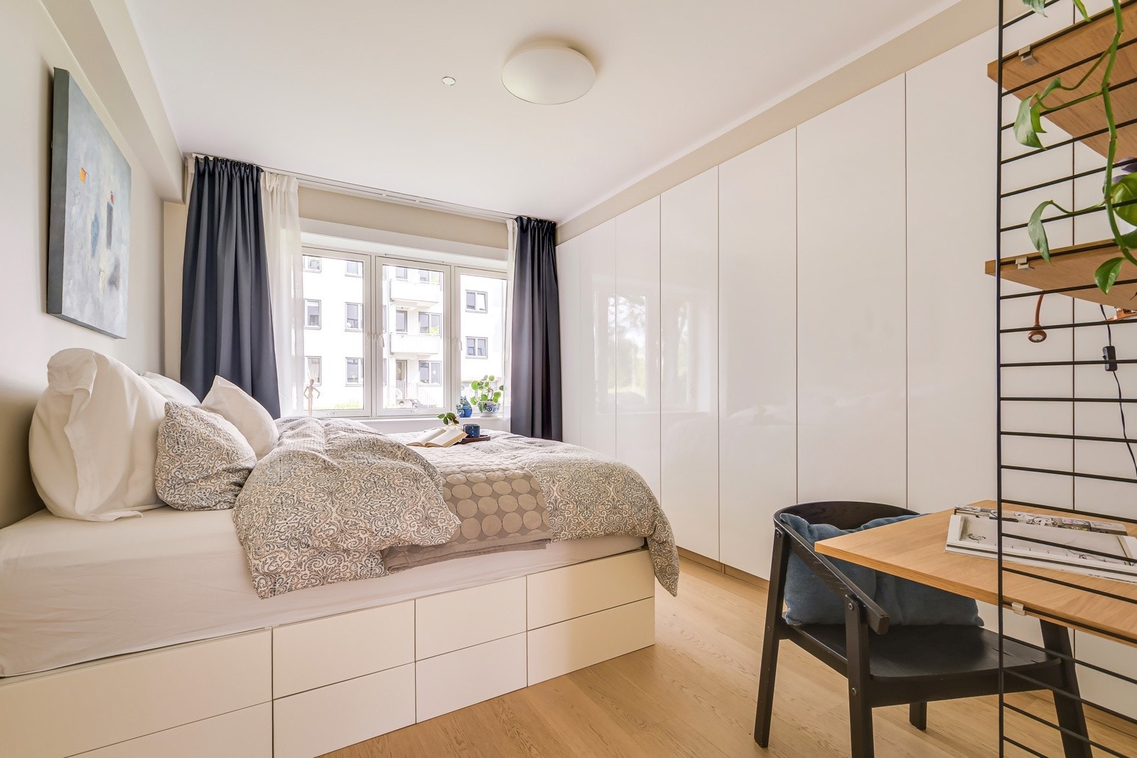 Langs den ene veggen står en hel innebygget garderobeløsning på ca. fire meter - medfølger i handelen - og gir rikelig med oppbevaringsplass til klær, sengetøy og det du ellers trenger å gjemme bort for et ryddig soveromsmiljø. Galleribilde