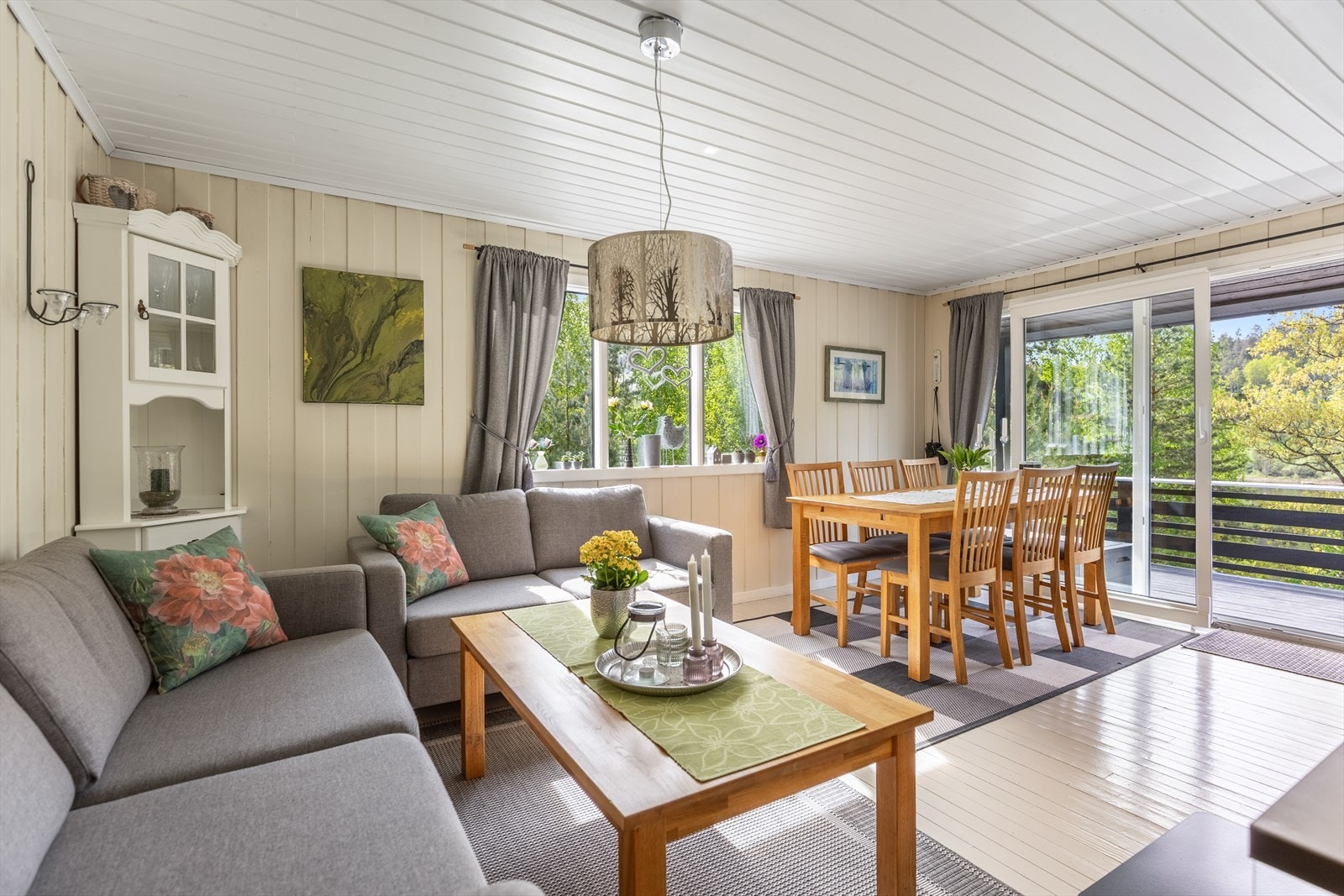 Stue med store vinduer og skyvedører som gir naturlig lys inn på hytta Galleribilde