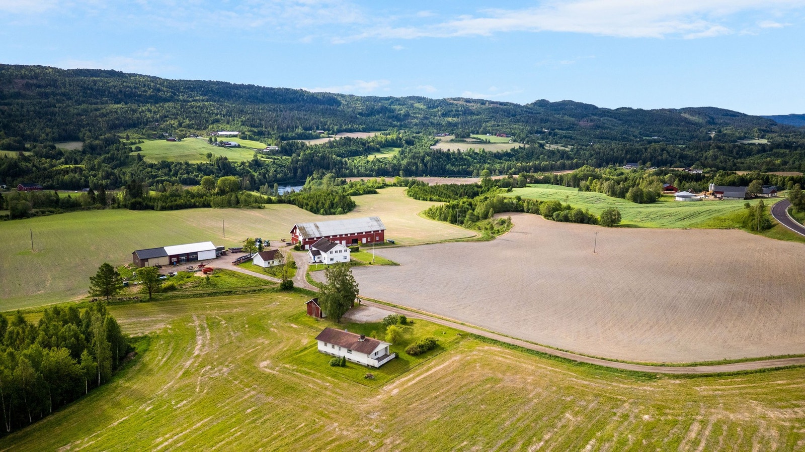 Landlig beliggenhet med jordsbruksområder og skogkledde åser. Galleribilde