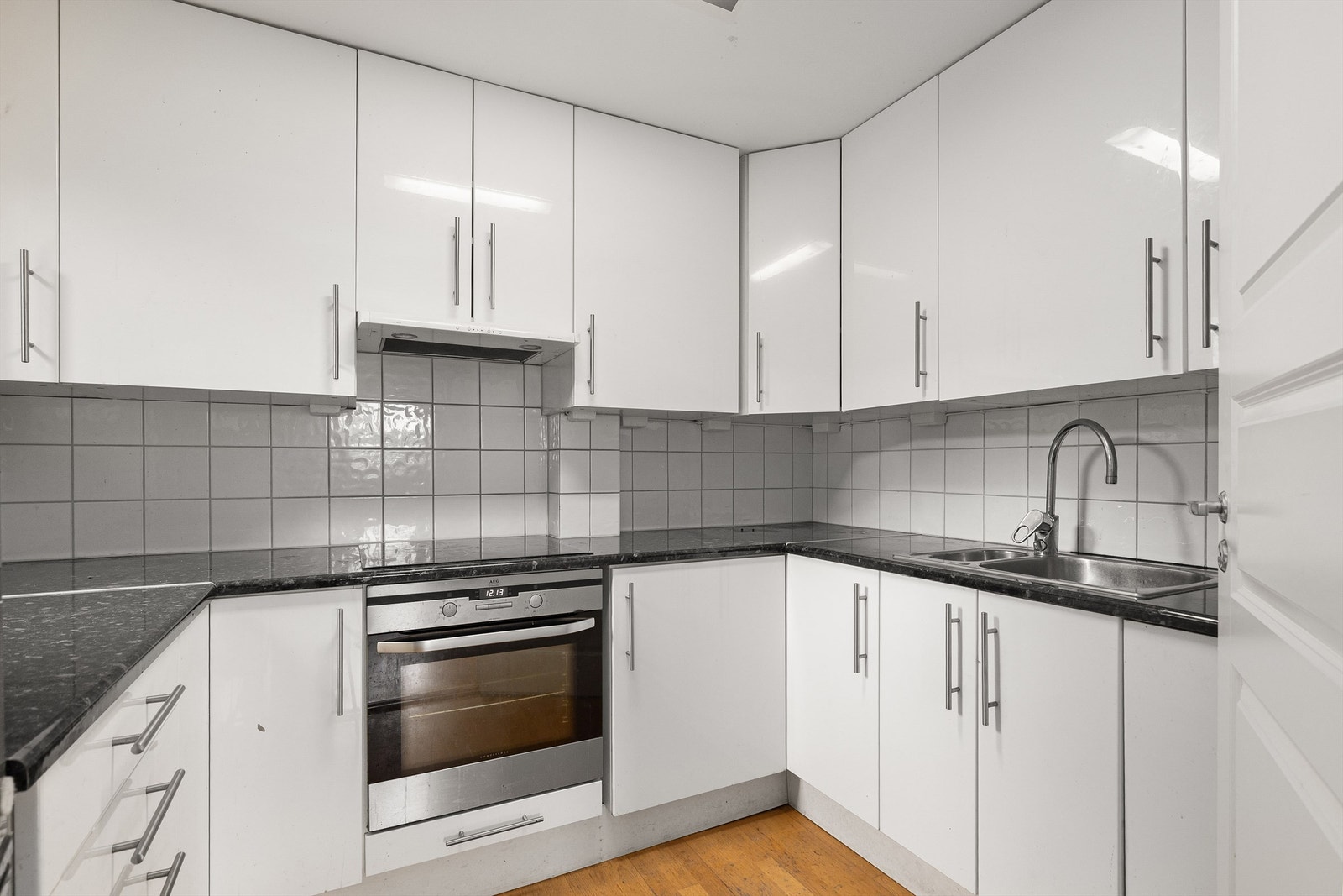 Kjøkken fra 2007 med hvite, slette fronter og integrerte hvitevarer Galleribilde