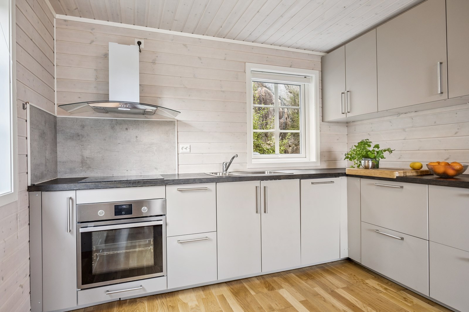 Tidløst og pent kjøkken med glatte overflater. Kjøkkenløsningen gir rom for en god arbeidsplass. Galleribilde