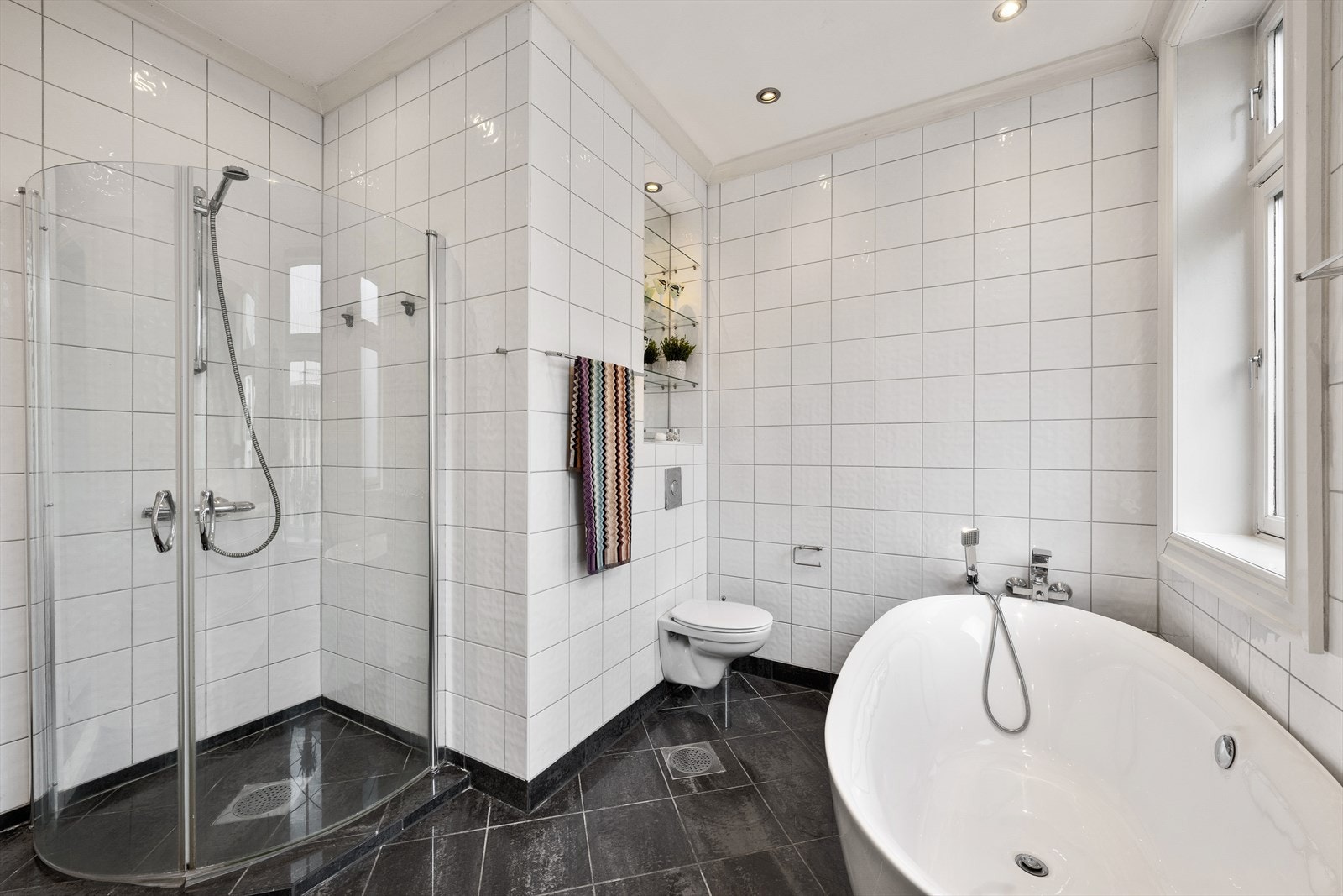 Badet har dusj med innfellbare dører i herdet glass, badekar og to servanter i helstøpt plate Galleribilde