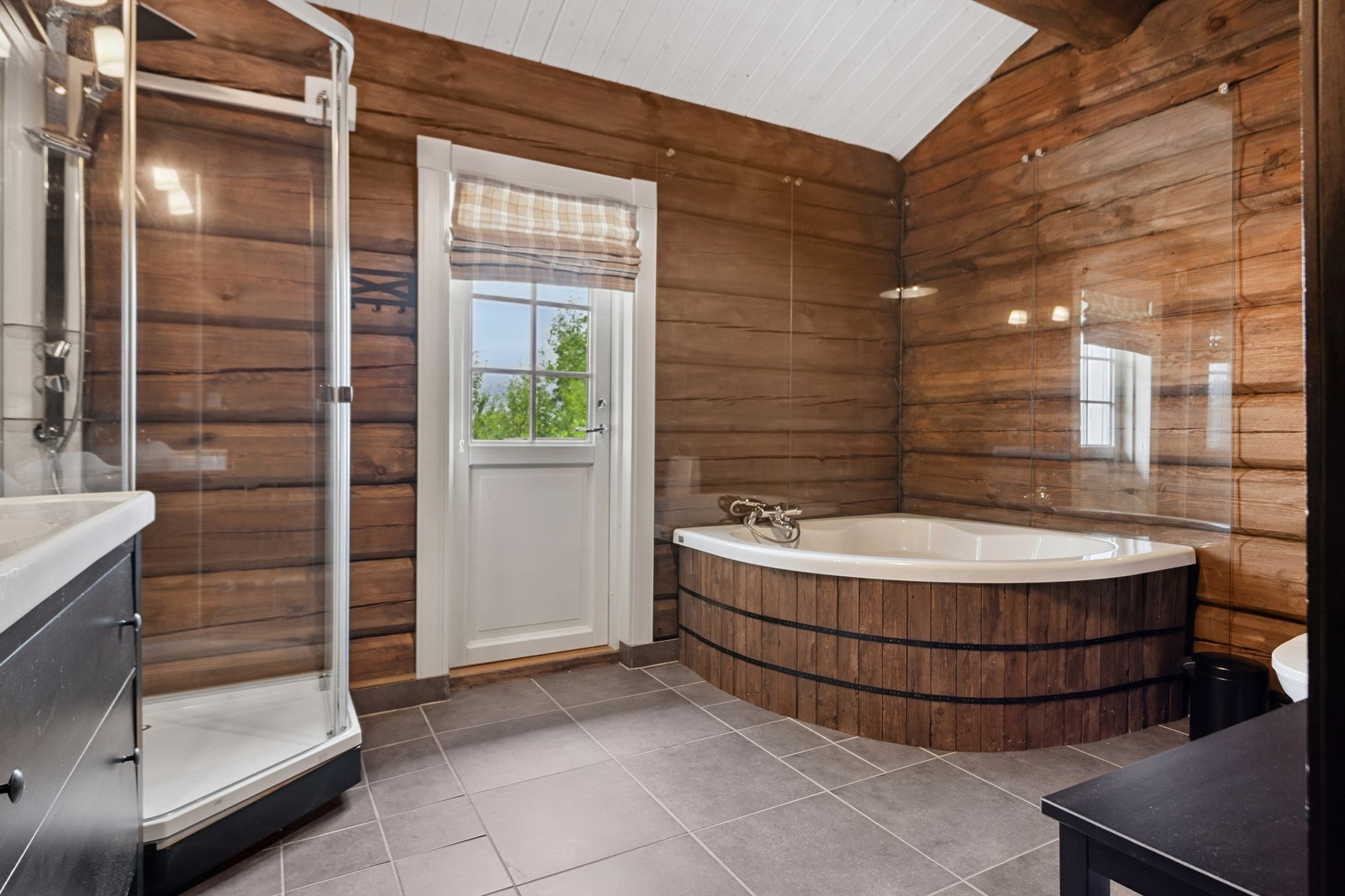 Romslig bad med både dusj og badekar med trepanel Galleribilde