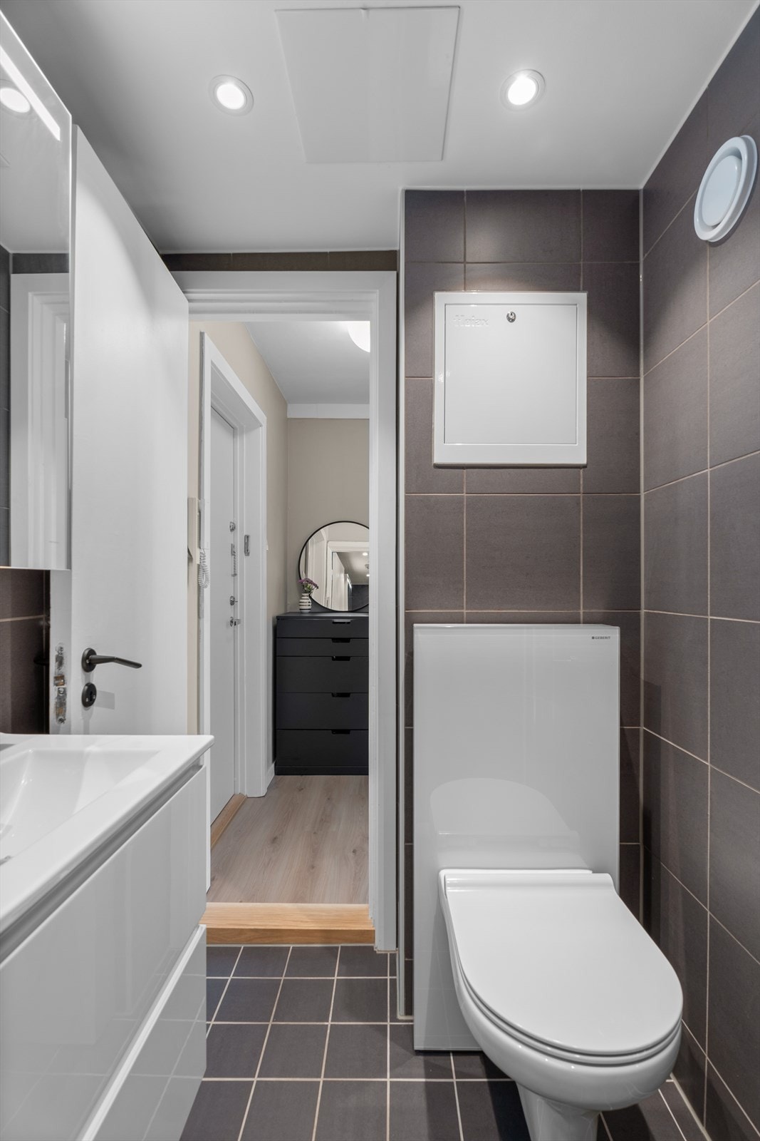 Innredningen består av servant, speilskap, vegghengt toalett og dusjhjørne med glassdører. Galleribilde