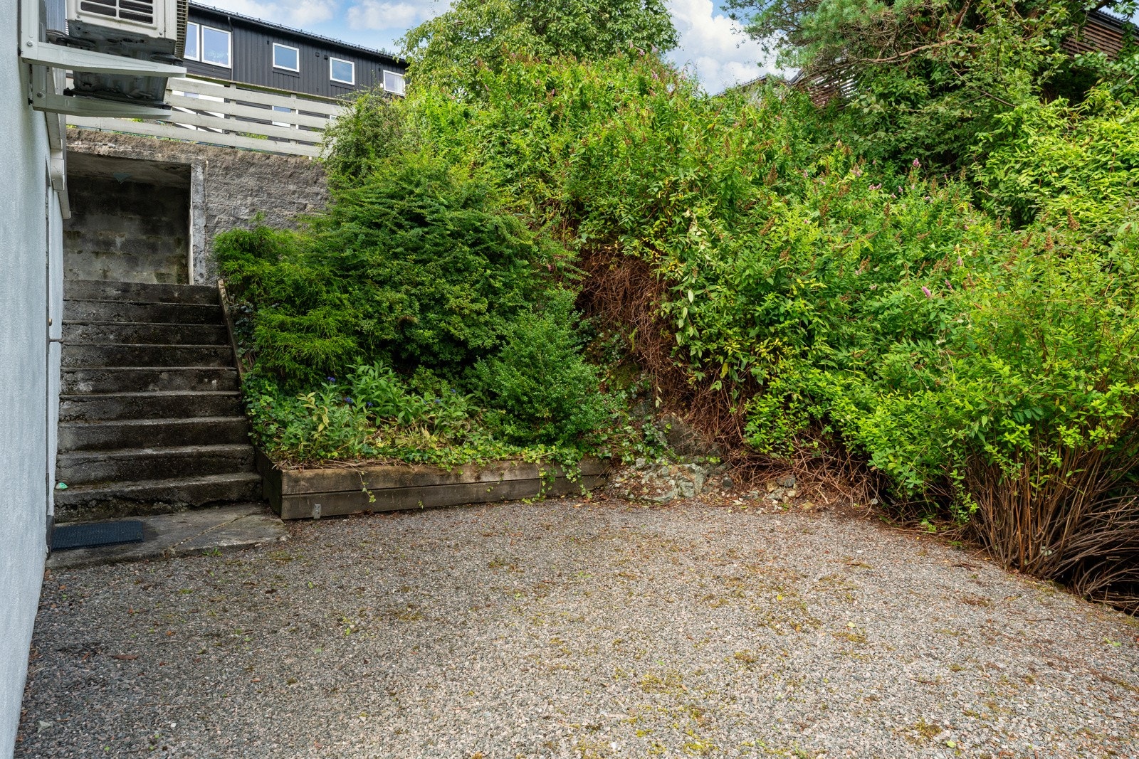 På nedsiden av huset er det egen inngang inn til underetasjen. På den grusede plassen foran underetasjen er det plass til flere sittegrupper og evt. også trampoline. Galleribilde