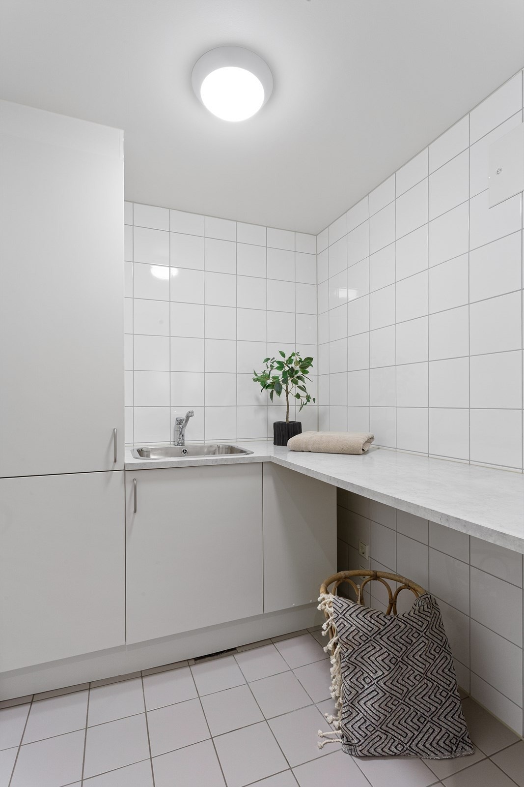 Flislagt vaskerom med gulvvarme. Innredning med hvite slette fronter. Opplegg for vaskemaskin. Galleribilde