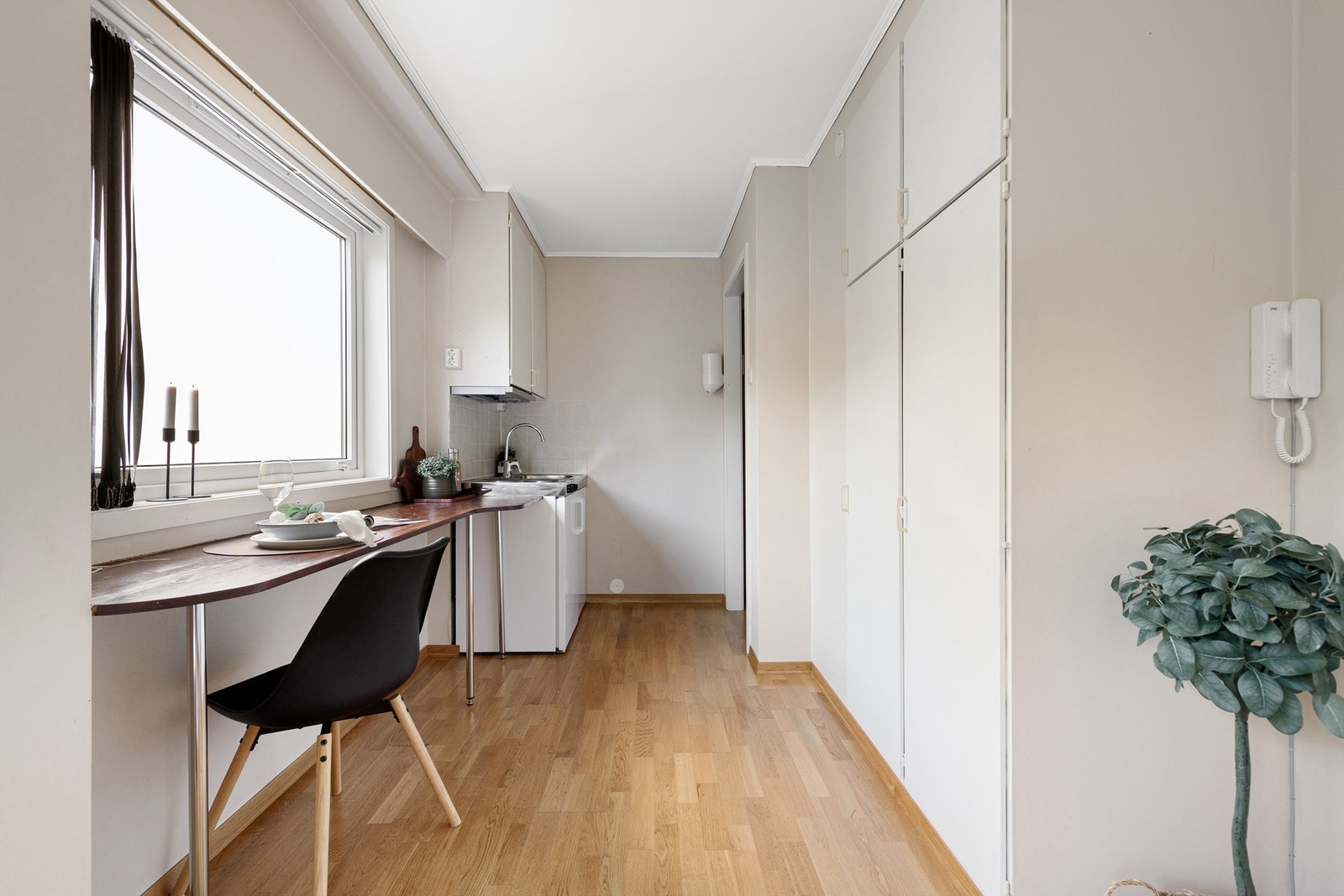 Stue/soverom og kjøkken i ett med fastmontert pult/spisebord ved vindu Galleribilde