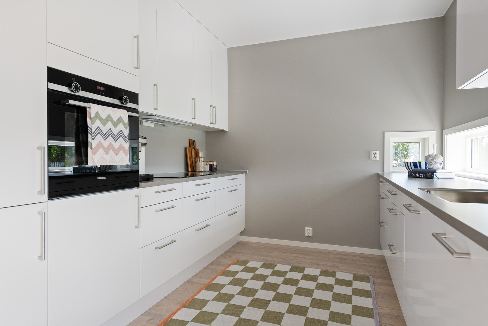 Innredningen har hvite, slette fronter, grå laminatbenkeplater og benkevinduer, samt ledbelysning. Galleribilde