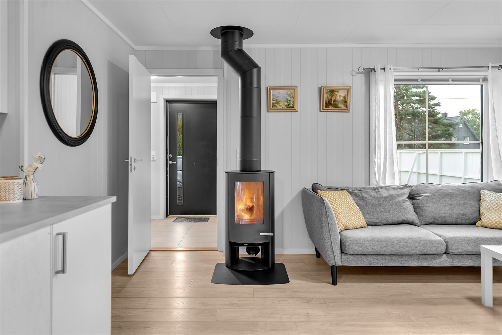 En varmepumpe sørger for behagelig temperatur året rundt, mens vedovnen fra 2025 tilfører både varme og en koselig atmosfære på kalde høst- og vinterkvelder. Galleribilde