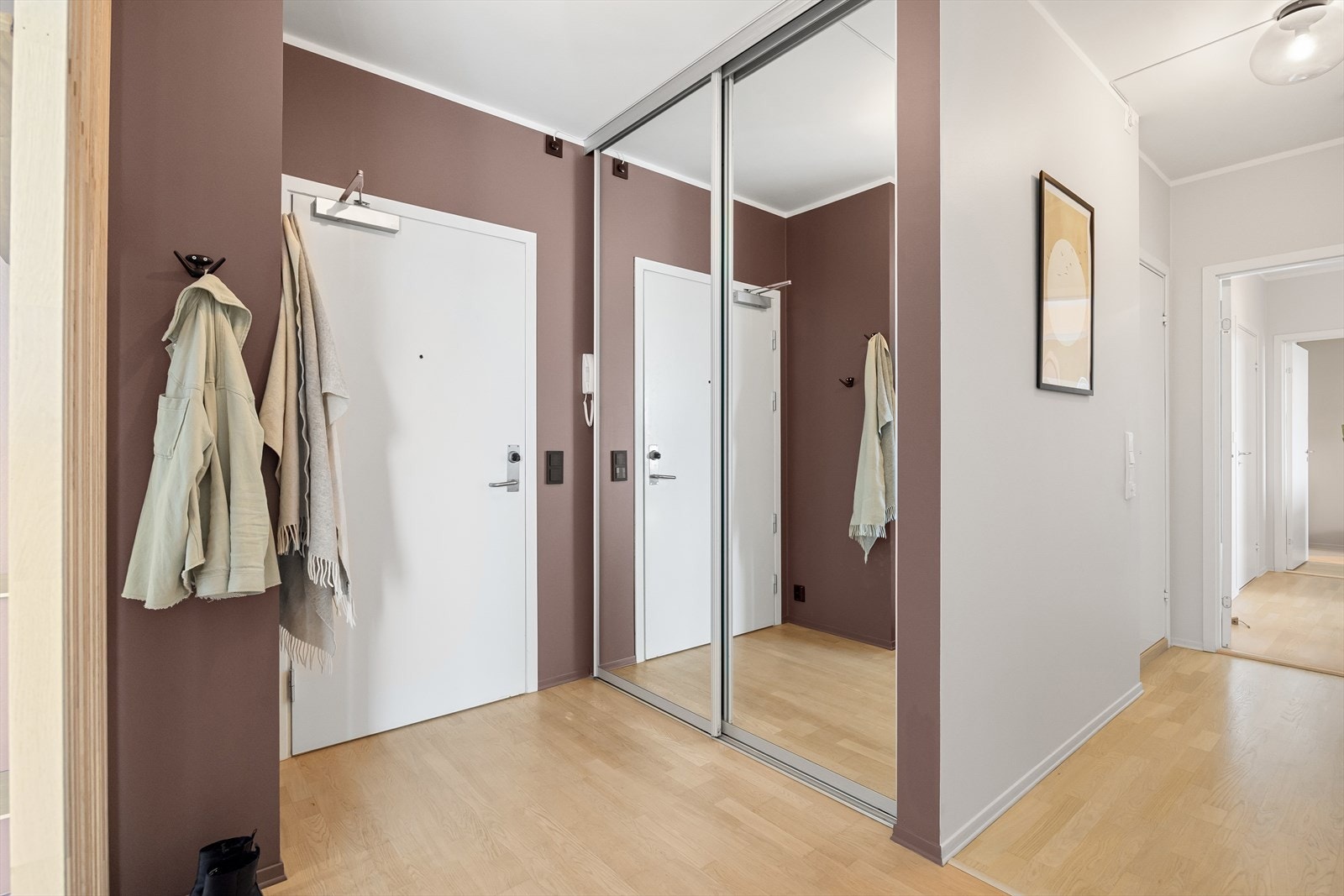 Velkommen inn! Leiligheten ønsker deg velkommen med en romslig og delikat entré. Her er det god plass til å henge fra seg yttertøy i en praktisk skyvedørsgarderobe med speilfronter. Galleribilde