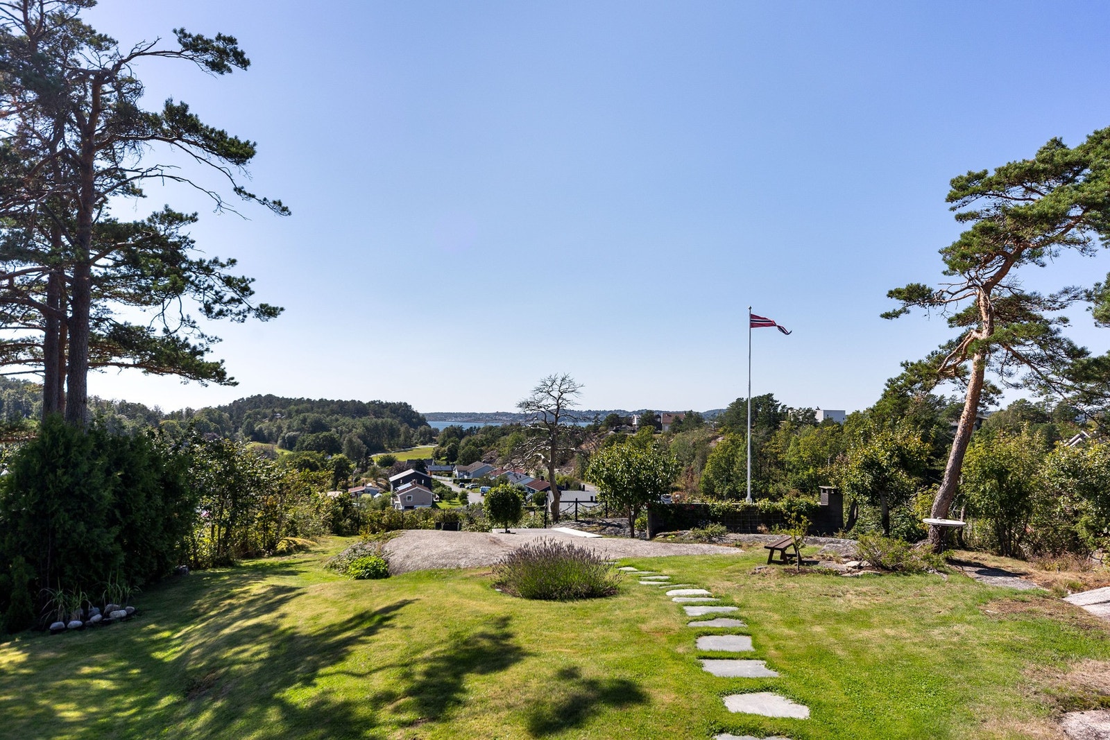 Stor hage med plen, beplantning og naturtomt. Usjenerte, solrike uteplasser med utsikt mot sjøen Galleribilde