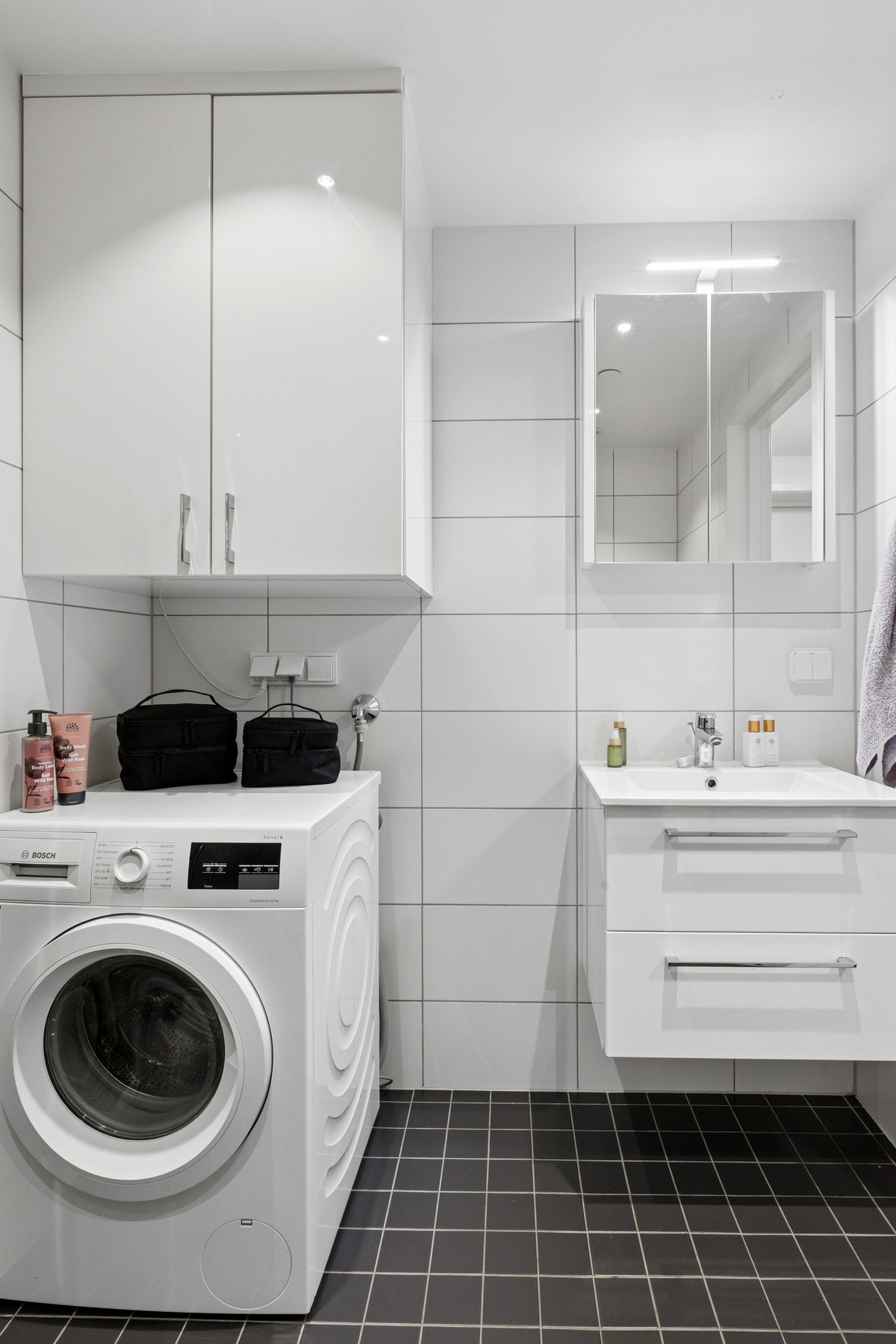 Badet innehar baderomsinnredning med servant, speil over vasken, vegghengt toalett og dusjhjørne med innfellbare dører. Galleribilde