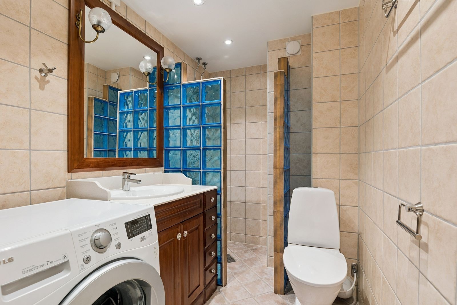 Pent flislagt bad med dusjhjørne og vaskemaskin. Galleribilde