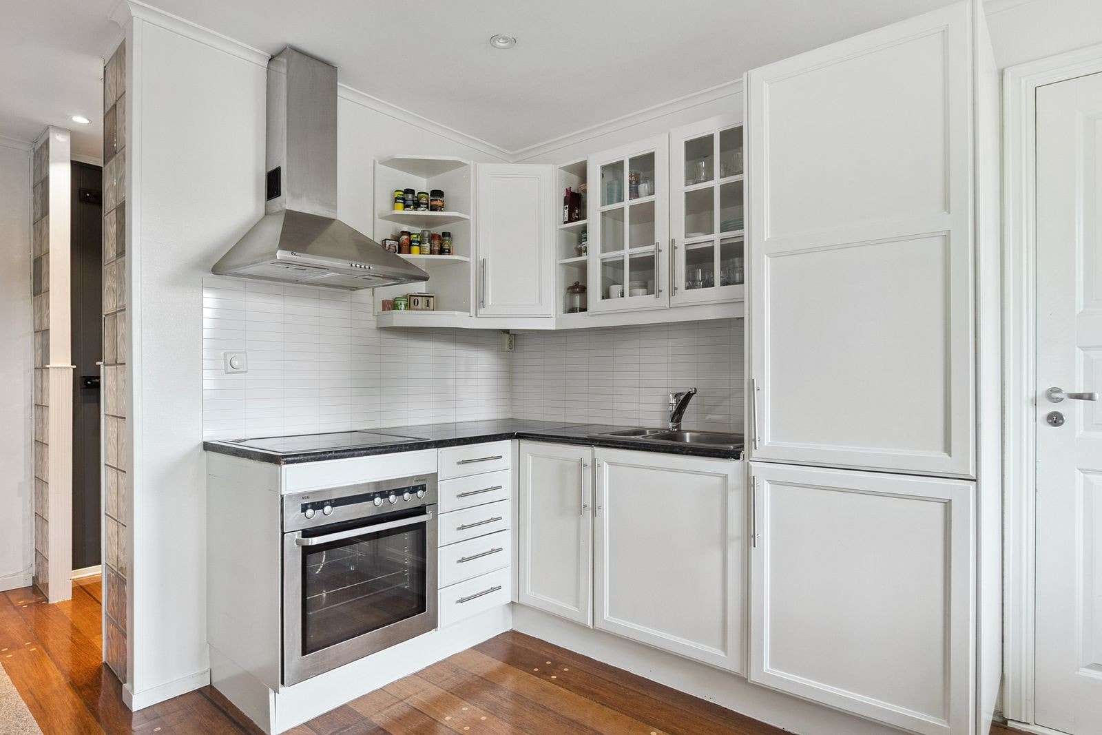 Pent kjøkken med komfyr, kombiskap og plass til spisebord. Galleribilde