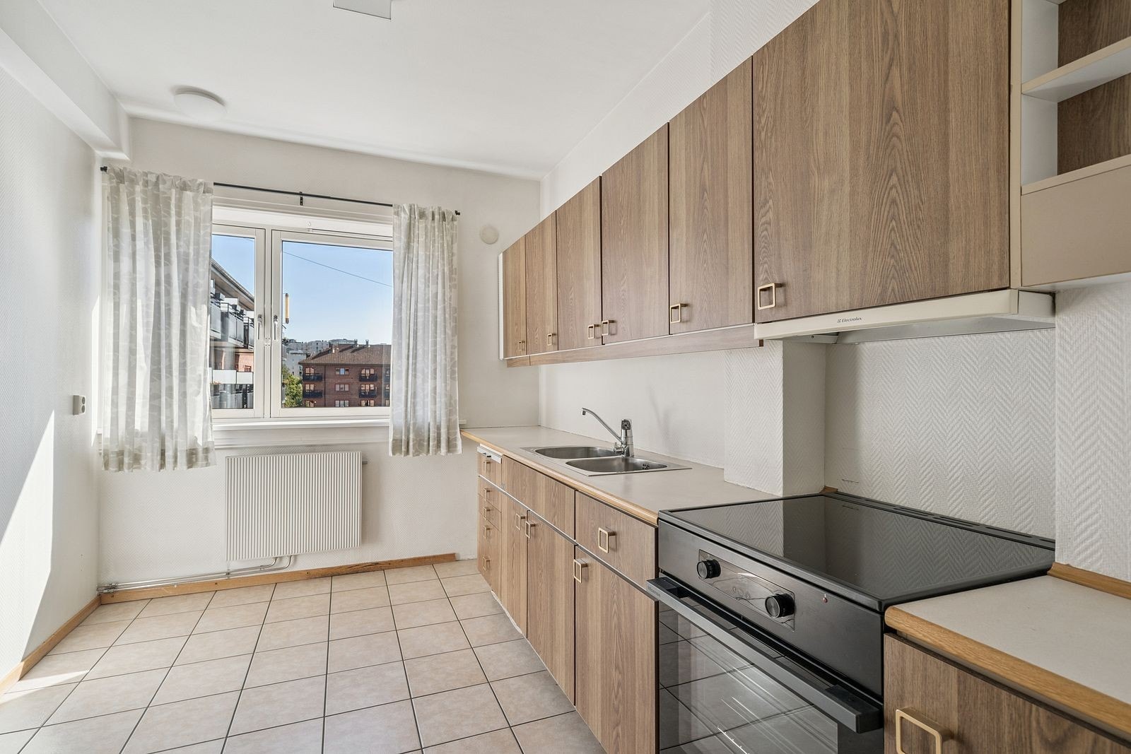 Kjøkken med komfyr og koketopp, godt med skap og benkeplass Galleribilde