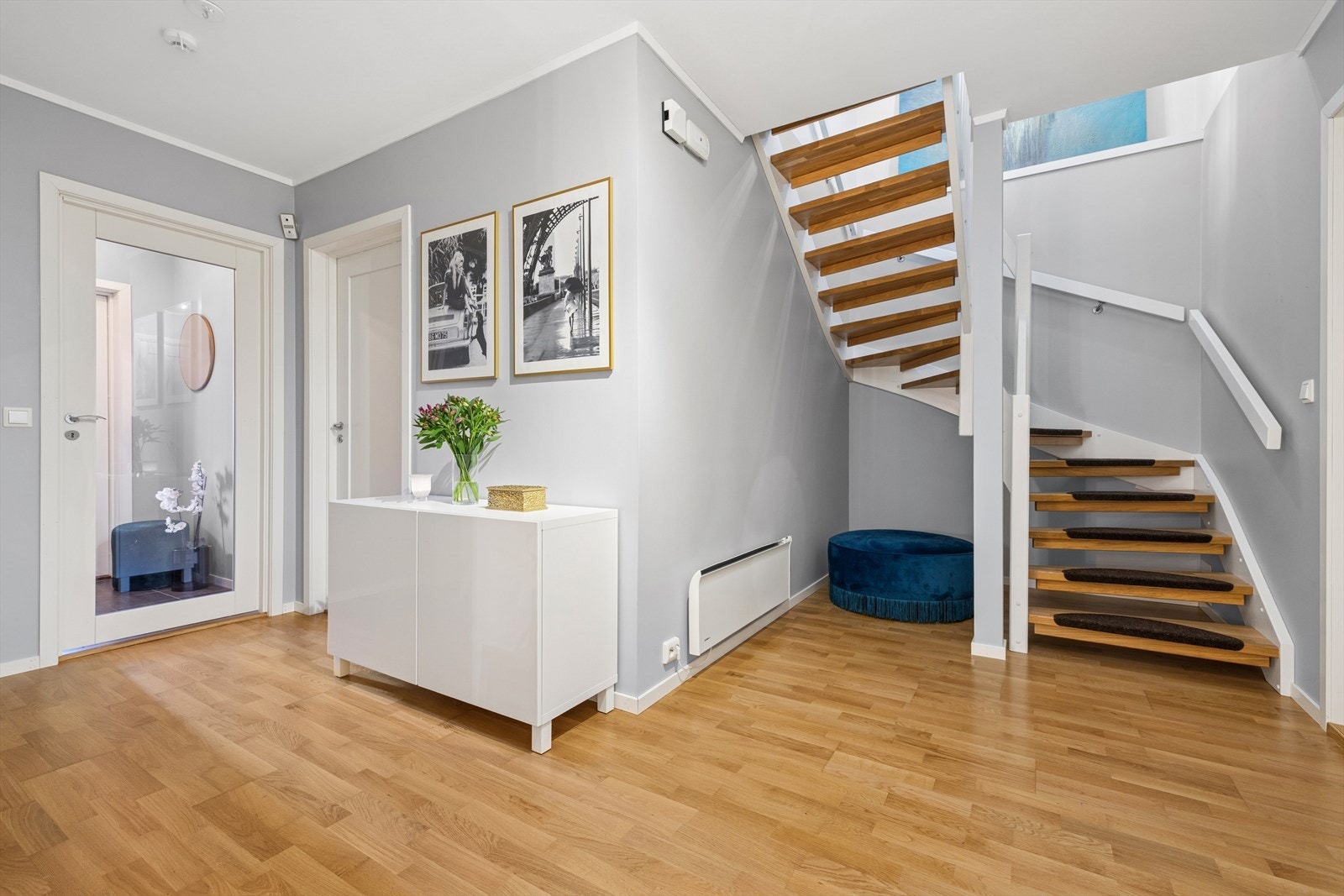 Romslig hall m/trapp med parkettgulv og nøytrale overflater. Galleribilde