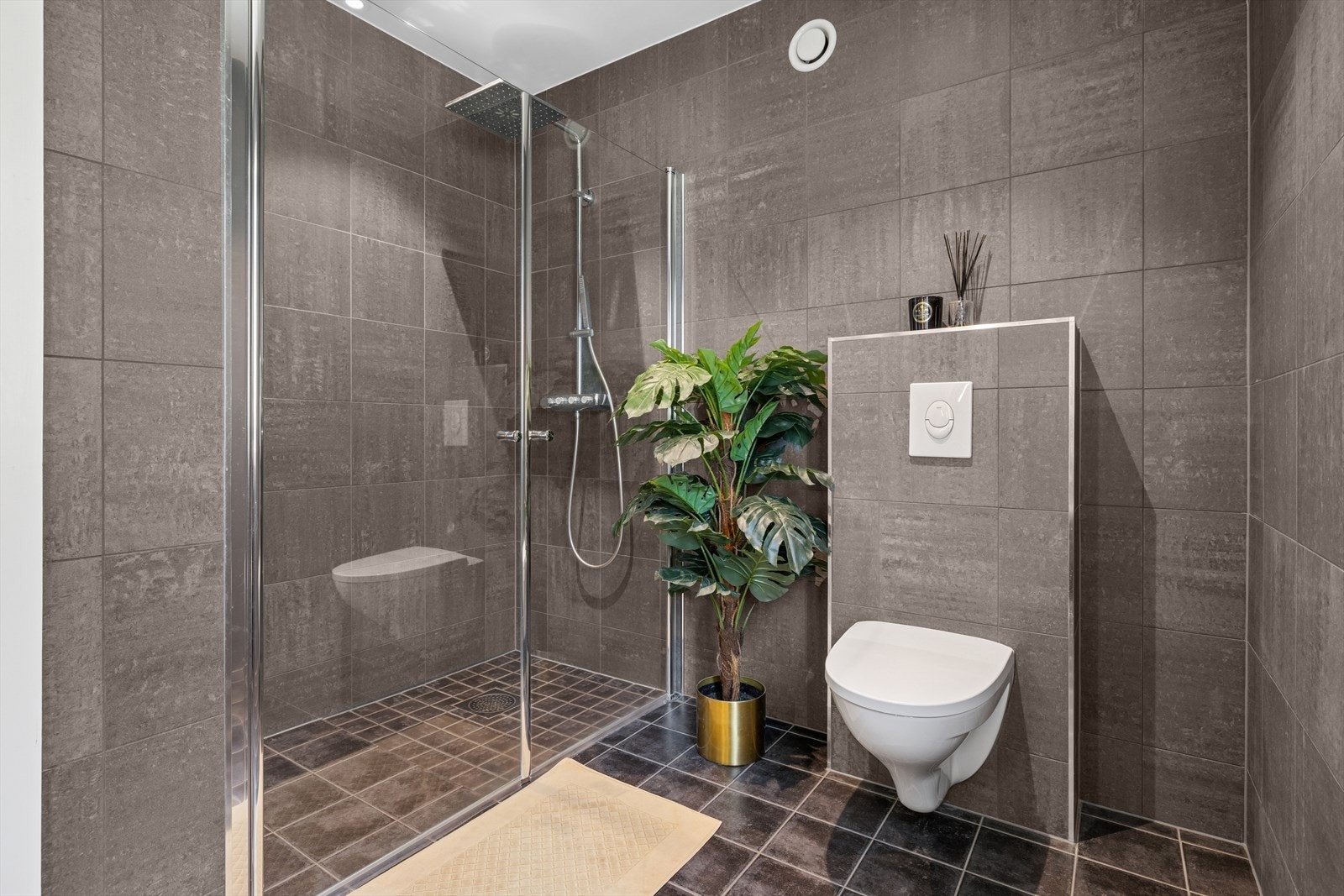 Badet er utstyrt med innredning med nedfelt servant, veggmontert toalett, høyskap og dusjvegger. Galleribilde