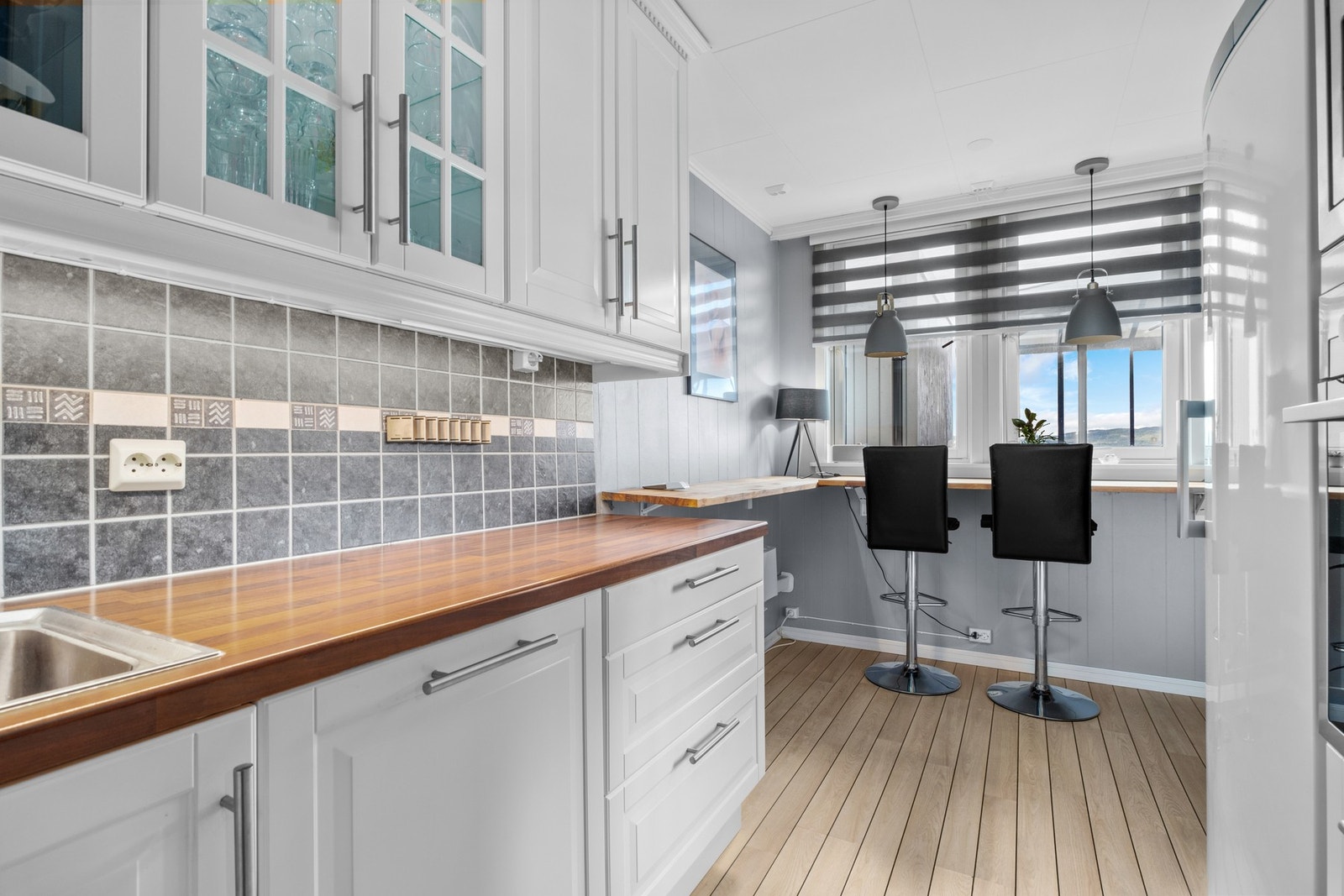 Laminat på gulv, og flis på vegg over benkeplate og malte plater på vegger. Galleribilde