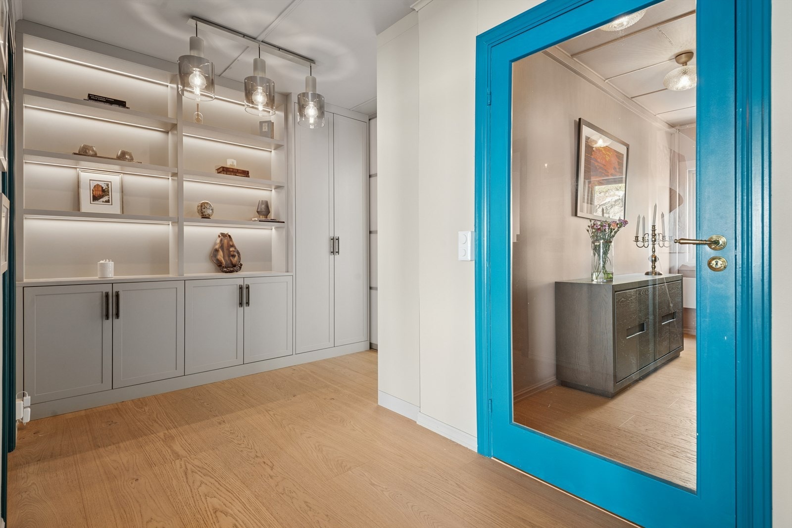 Mellomgang med spesialtilpasset og møbelsnekret hylle/-skapløsning i moderne utførelse med lekre farge og lyssettinger. Galleribilde