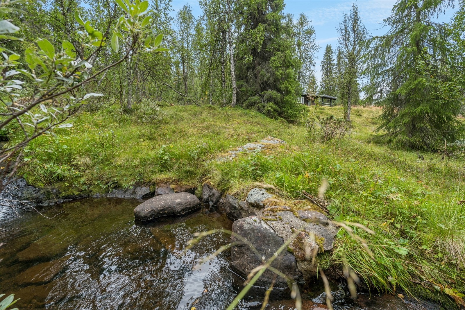 Eiendommen grenser mot en liten bekk i enden av tomta, som bidrar til den landlige og rolige atmosfæren. Galleribilde