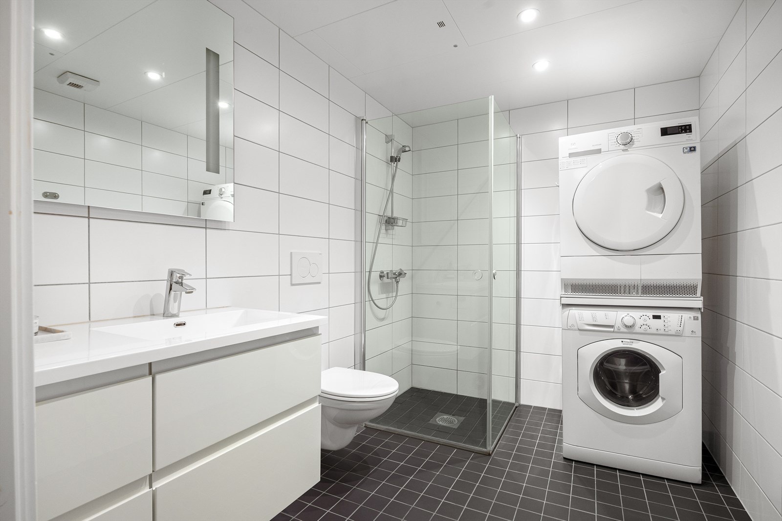 Pent, flislagt baderom med gulvvarme og downlights i himlingen. Badet er innredet med servantskap med nedfelt servant, veggskap med speil og integrert belysning, vegghengt toalett med innebygd sisterne samt dusjsone med innfelte dusjdører i herdet glass. Galleribilde