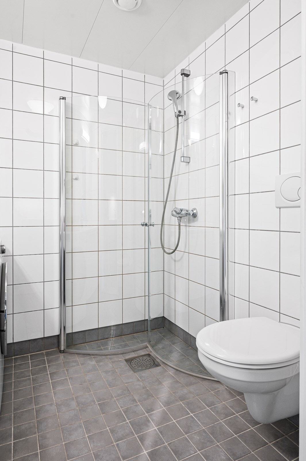 Videre har badet dusjhjørne med svingbare glassdører og vegghengt klosett. Det er opplegg for vaskemaskin. Galleribilde
