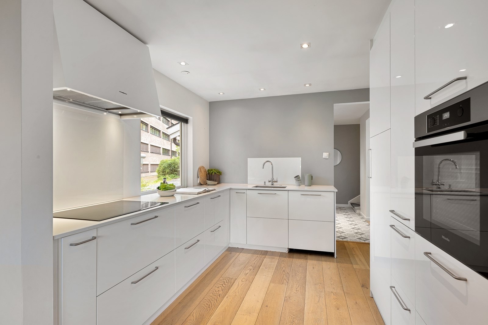 Kjøkkenet har hvite, glatte fronter og downlights i himling Galleribilde