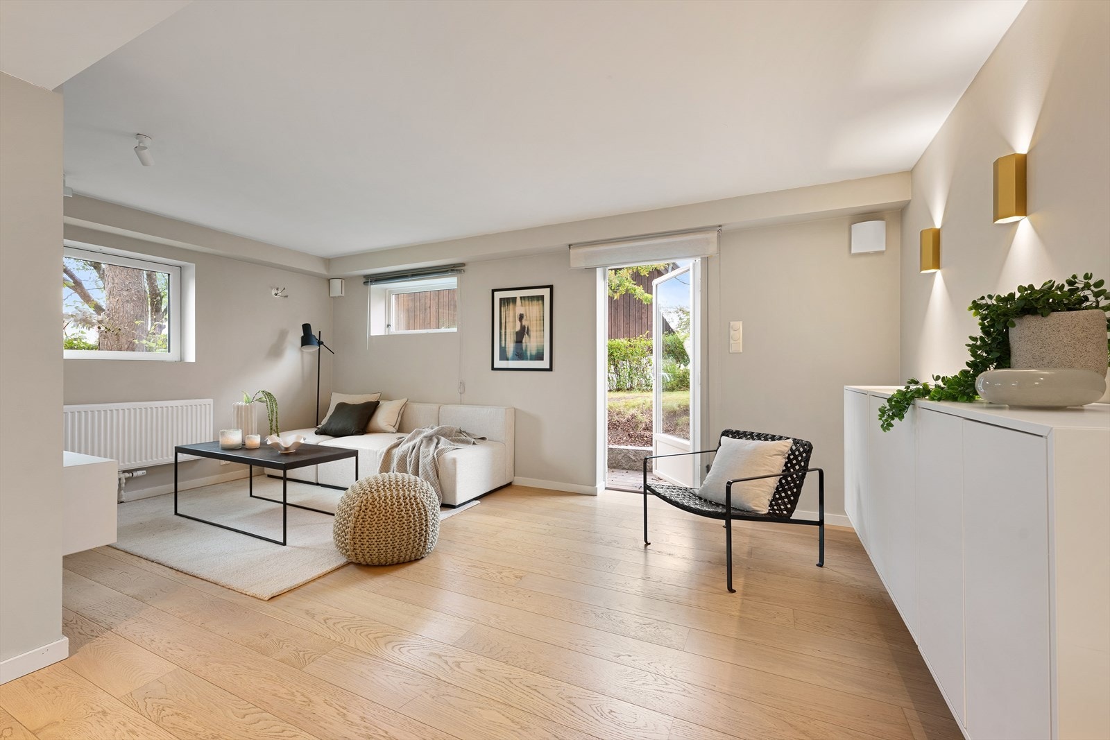 Lys kjellerstue med plass til sofaseksjon, sofabord og mediemøblement - Videre adkomst til eiendommens hage Galleribilde