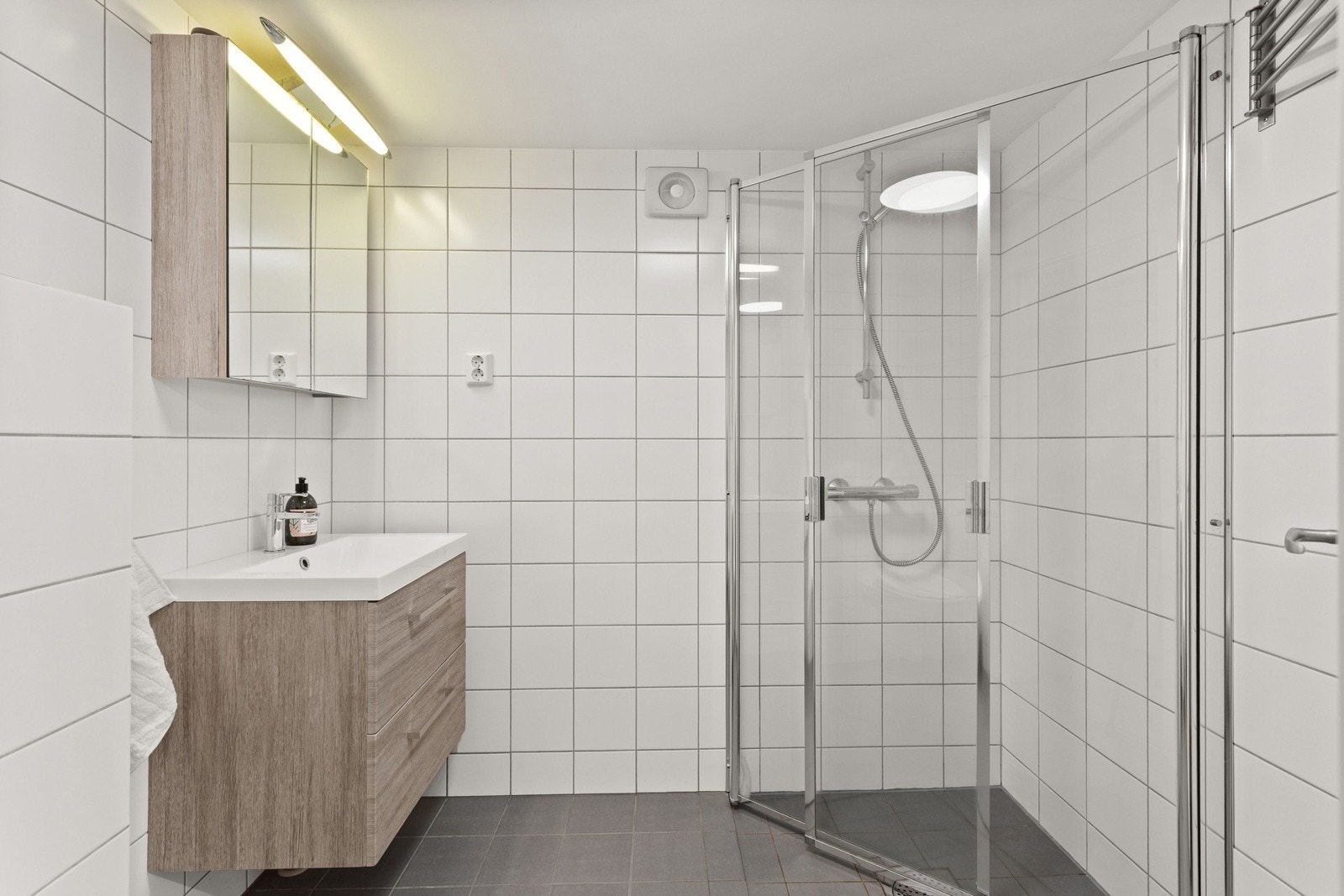 Delikat, flislagt bad med varmekabler i gulv. Rommet har innredning med nedfelt servant, veggmontert toalett og dusjvegger/hjørne. Galleribilde