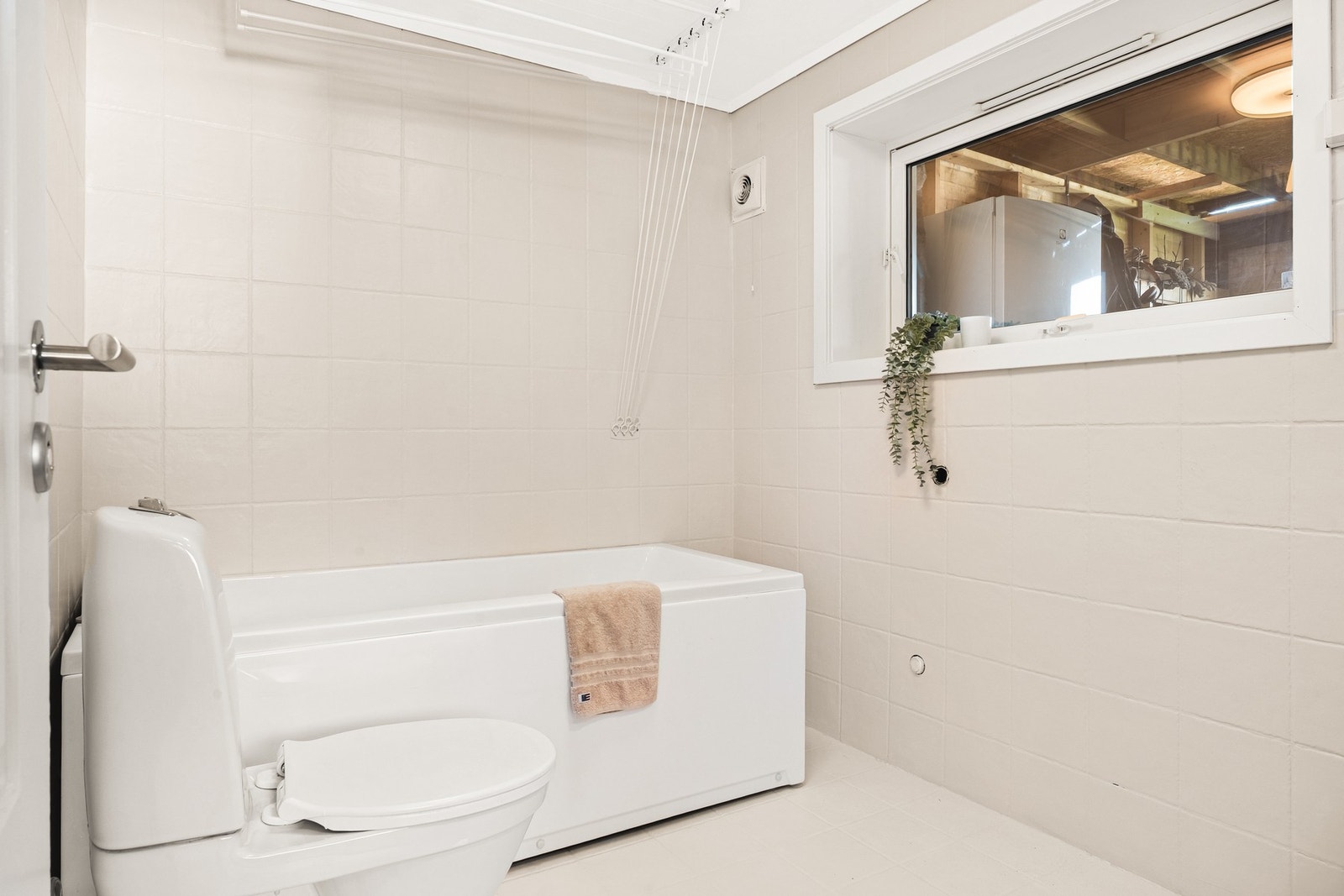 Badet i underetasjen er helfliset og har en slett malt himling. Det er innredet med badekar, vegghengt toalett og baderomsinnredning. Galleribilde