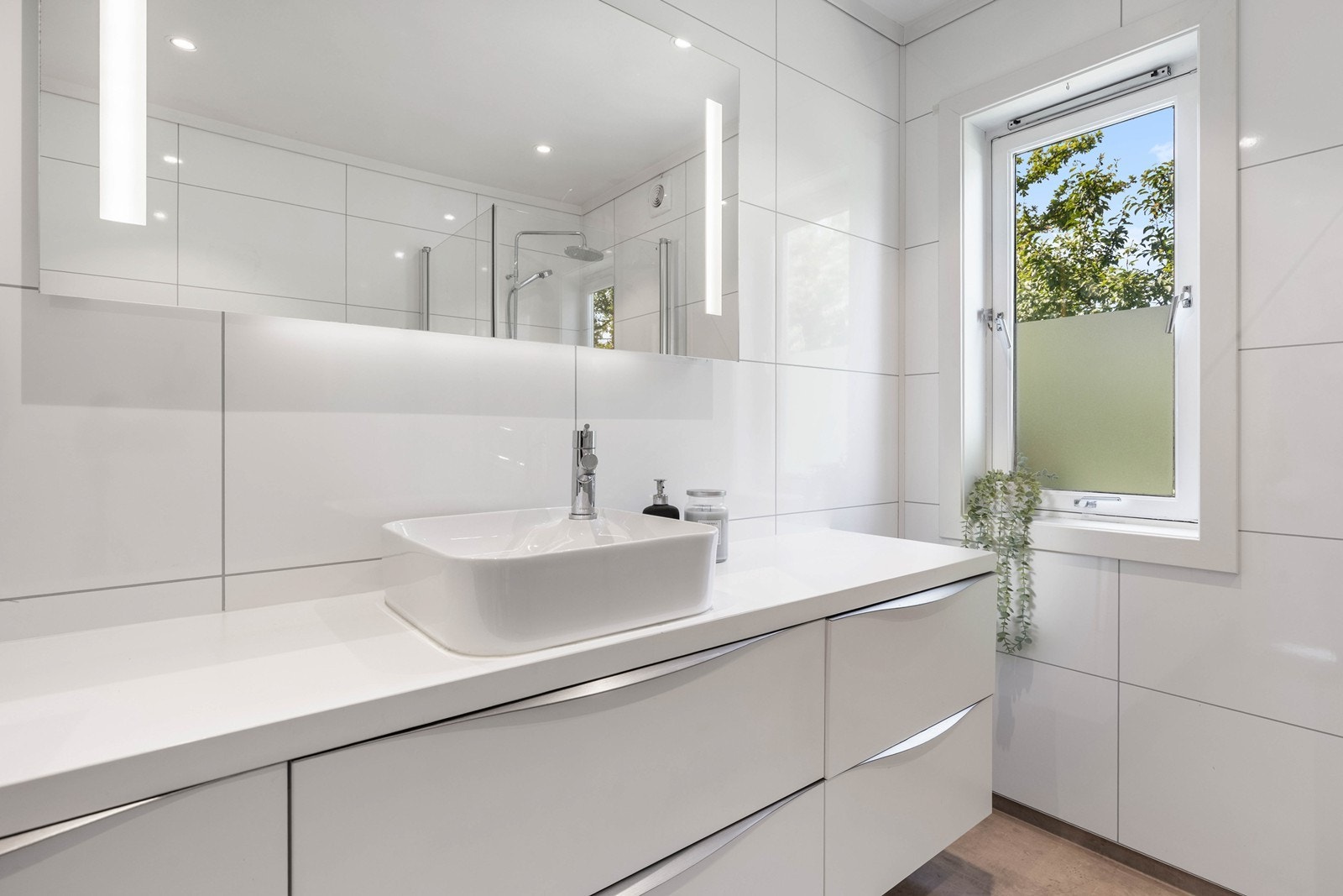 Innredet med servant, speil med lys, dusjhjørne og wc. Galleribilde