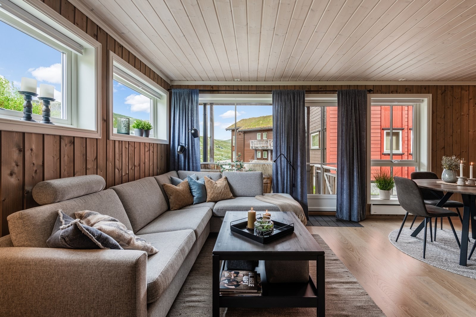 Stue med parkett på gulv og tidsriktig beiset panel på vegger. Direkte utgang fra terrasse gjør livet enkelt når en vil raskt ut i naturen! Eller bare lufte hunden en kort tur. Galleribilde