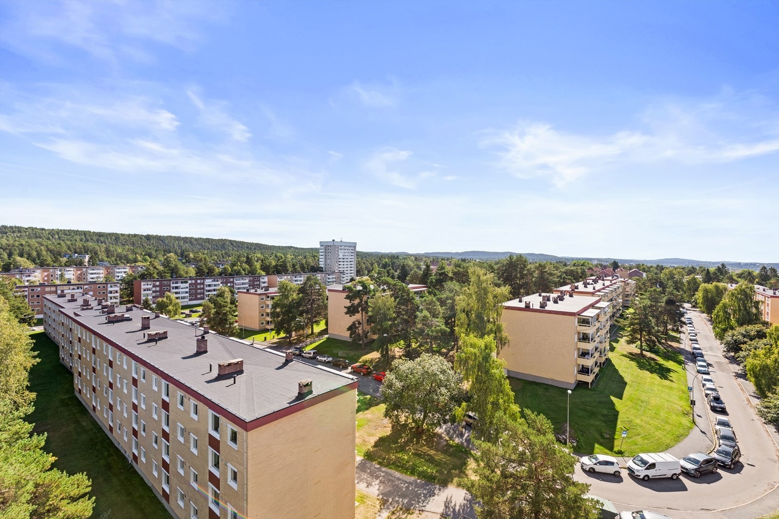 Utsikt over borettslagets fellestomt. Borettslaget har en stor, barnevennlig og trafikkskjermet felleseiendom som er flott opparbeidet med store, velstelte plenarealer rundt og mellom blokkene samt noe naturtomt med fjell i dagen og fullvoksne trær. Galleribilde