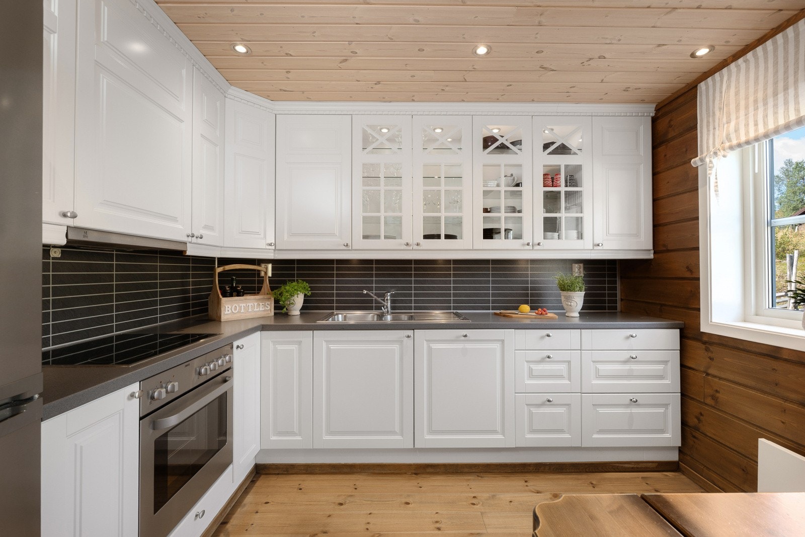 Kjøkkenet har en klassisk innredning med laminerte skrog, profilerte fronter - hvorav enkelte er med glass og laminert benkeplate med kjøkkenkum. Galleribilde